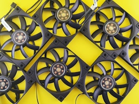 Multiple black computer fans arranged on yellow background