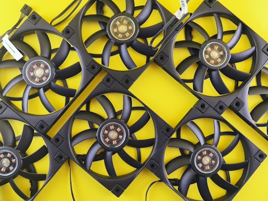 Multiple black computer fans arranged on yellow background