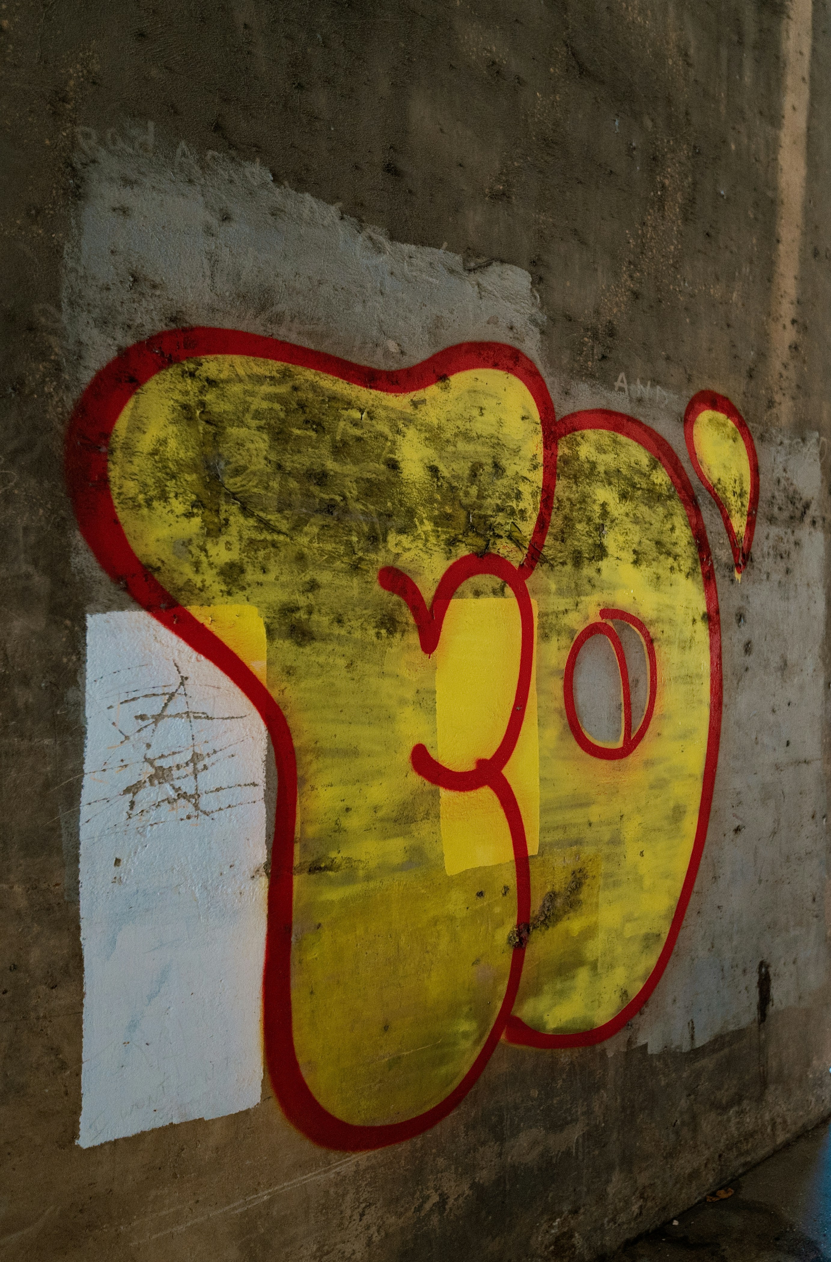 Yellow graffiti with red outline on concrete wall