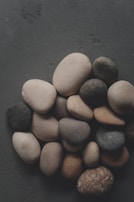 Pile of smooth, varied stones on a dark surface.