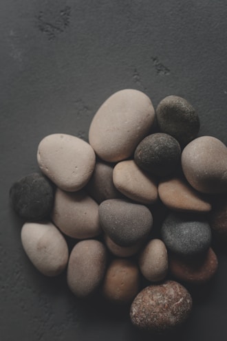 Pile of smooth, varied stones on a dark surface.