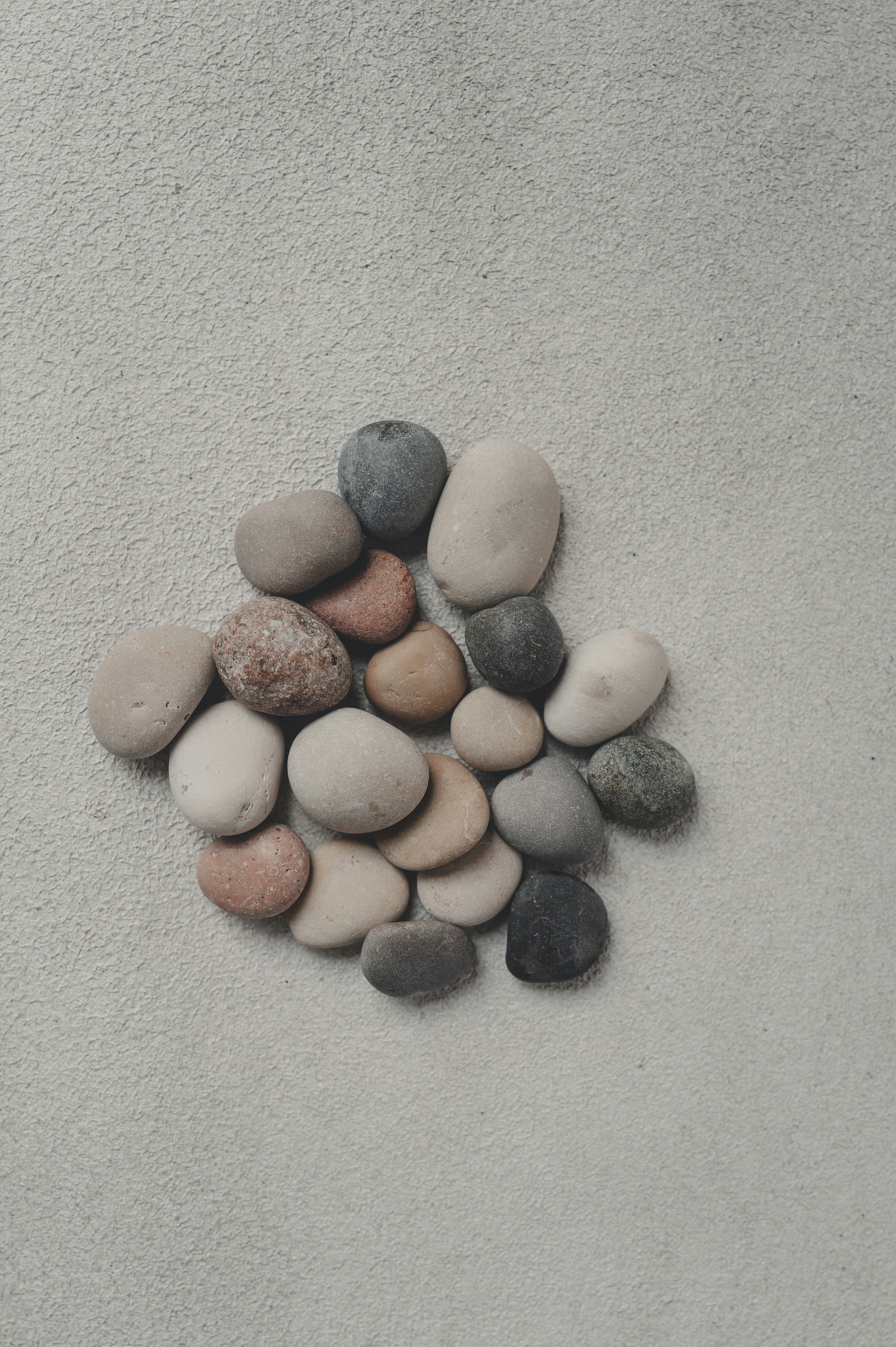 Smooth, colorful stones arranged on a sandy surface.