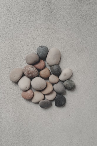 Smooth, colorful stones arranged on a sandy surface.