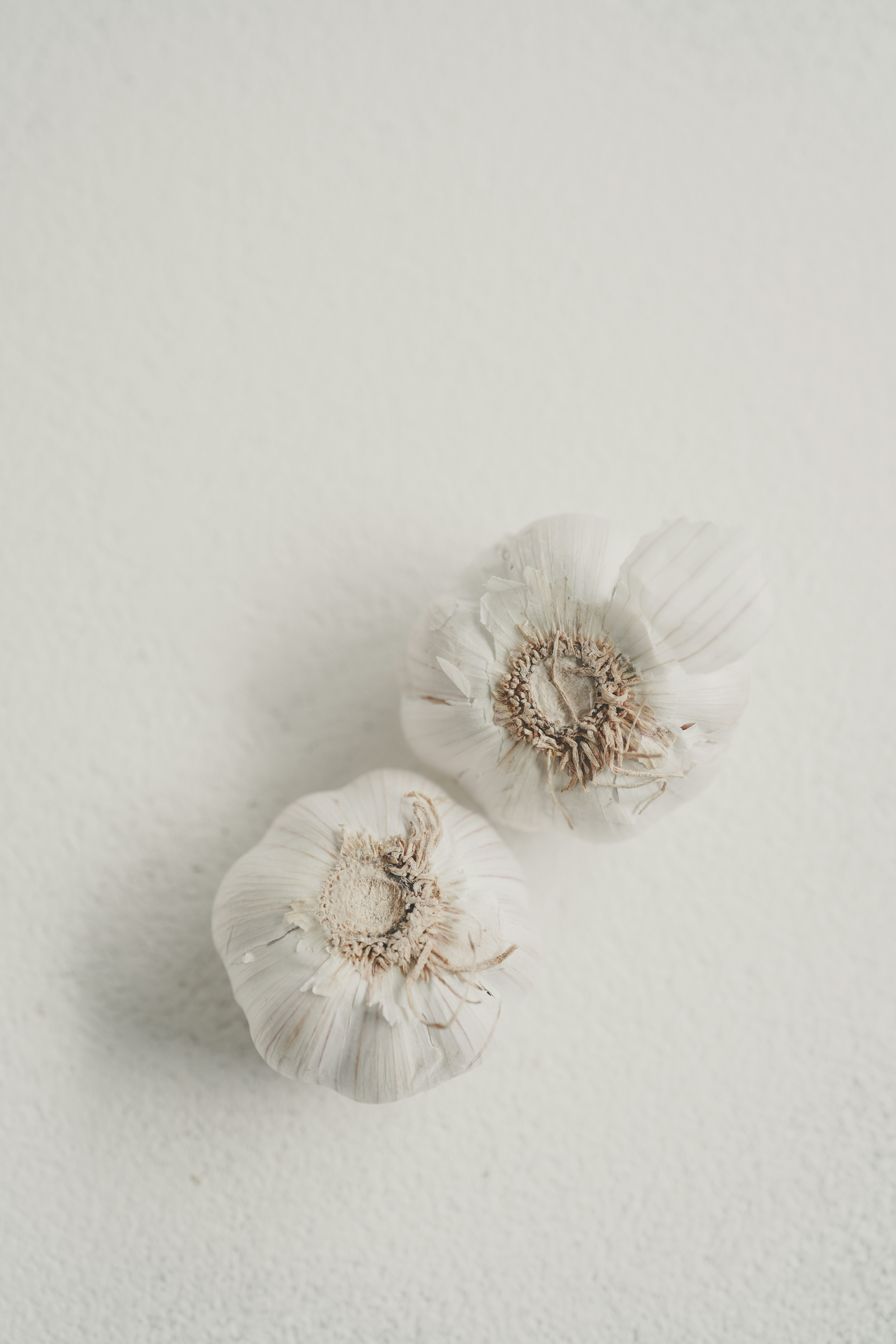 Zwei Knoblauchzehen auf einer strukturierten Oberfläche.