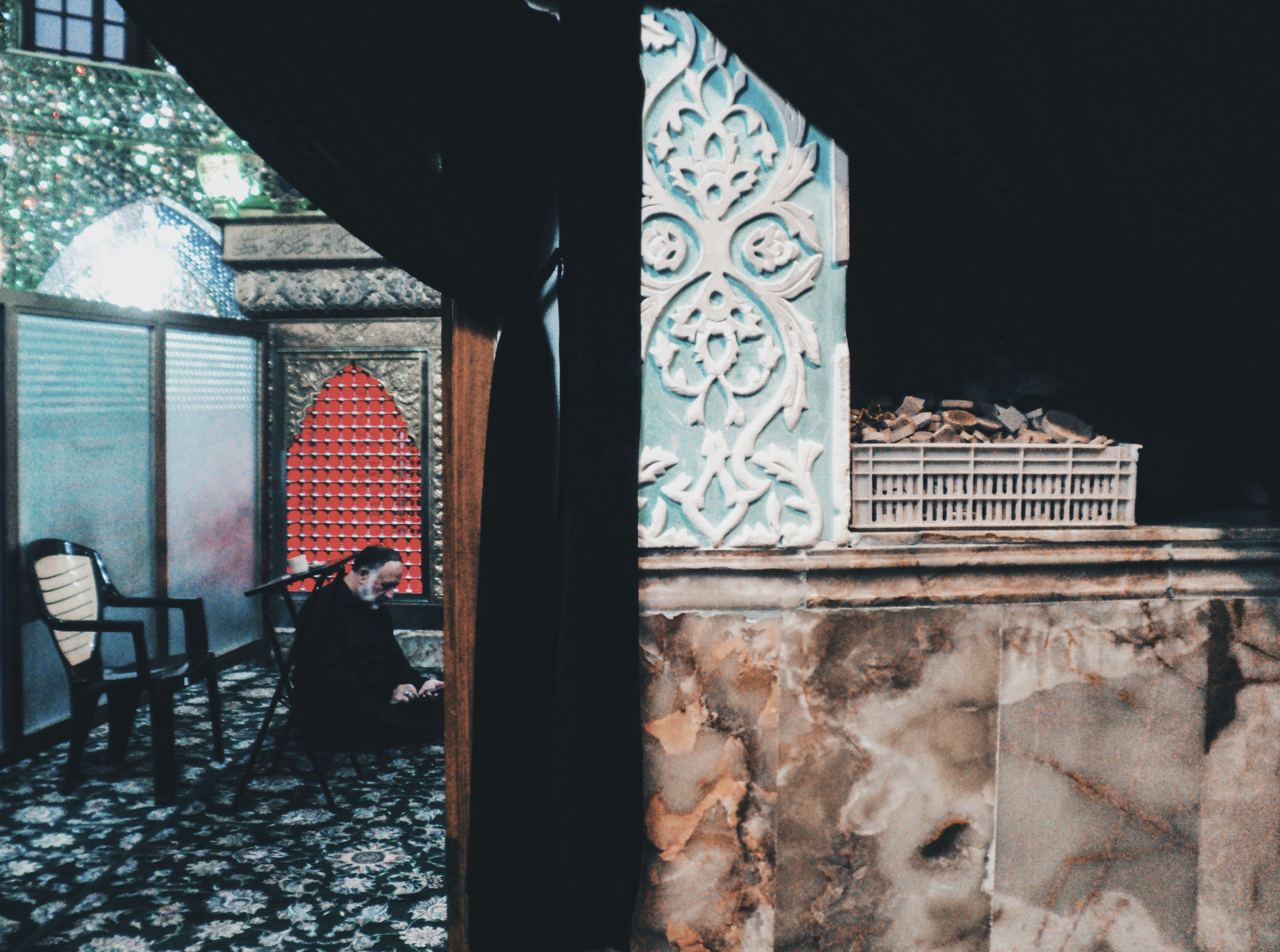 Person praying in a dimly lit, ornate structure