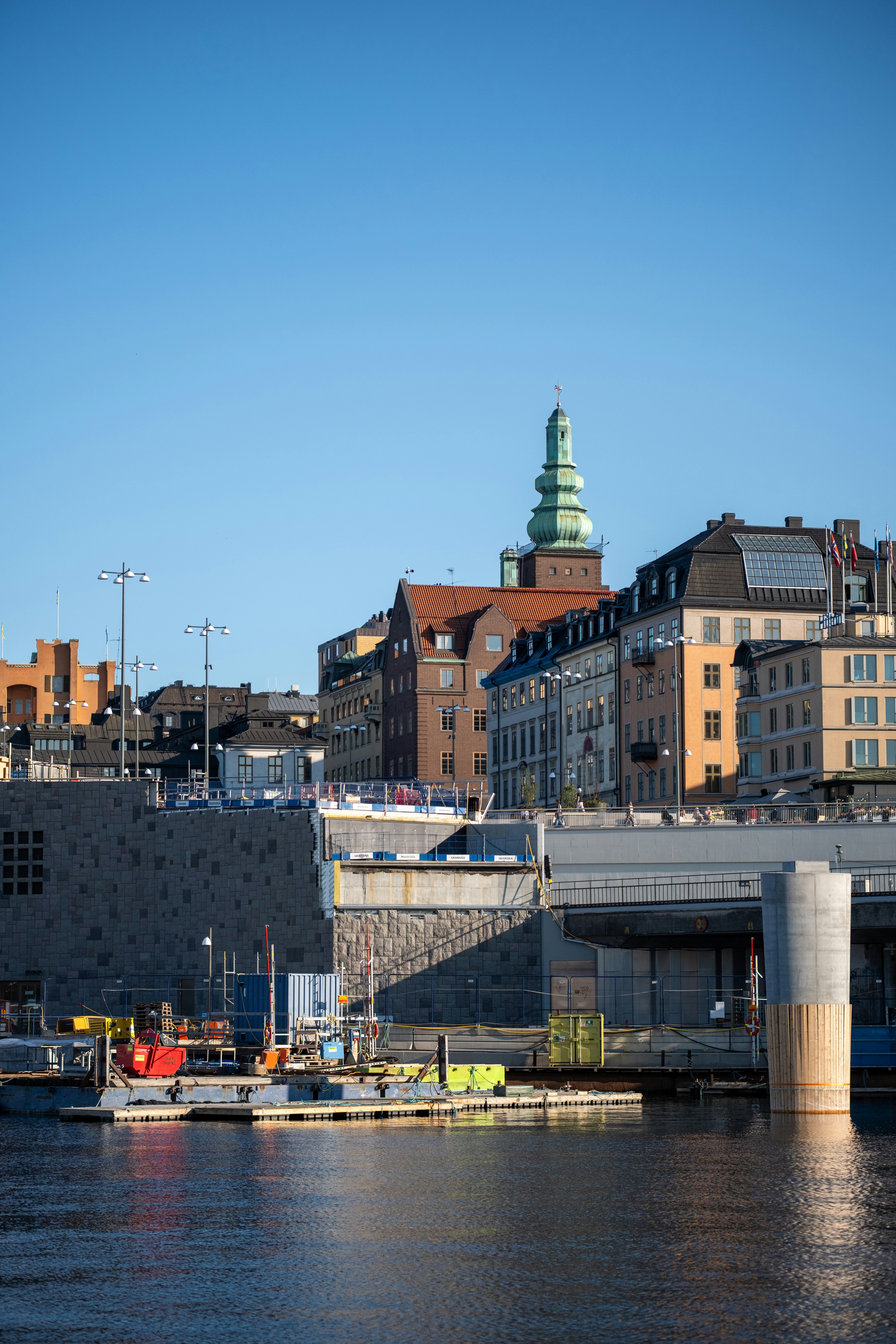 City skyline with waterfront buildings and clear blue sky.