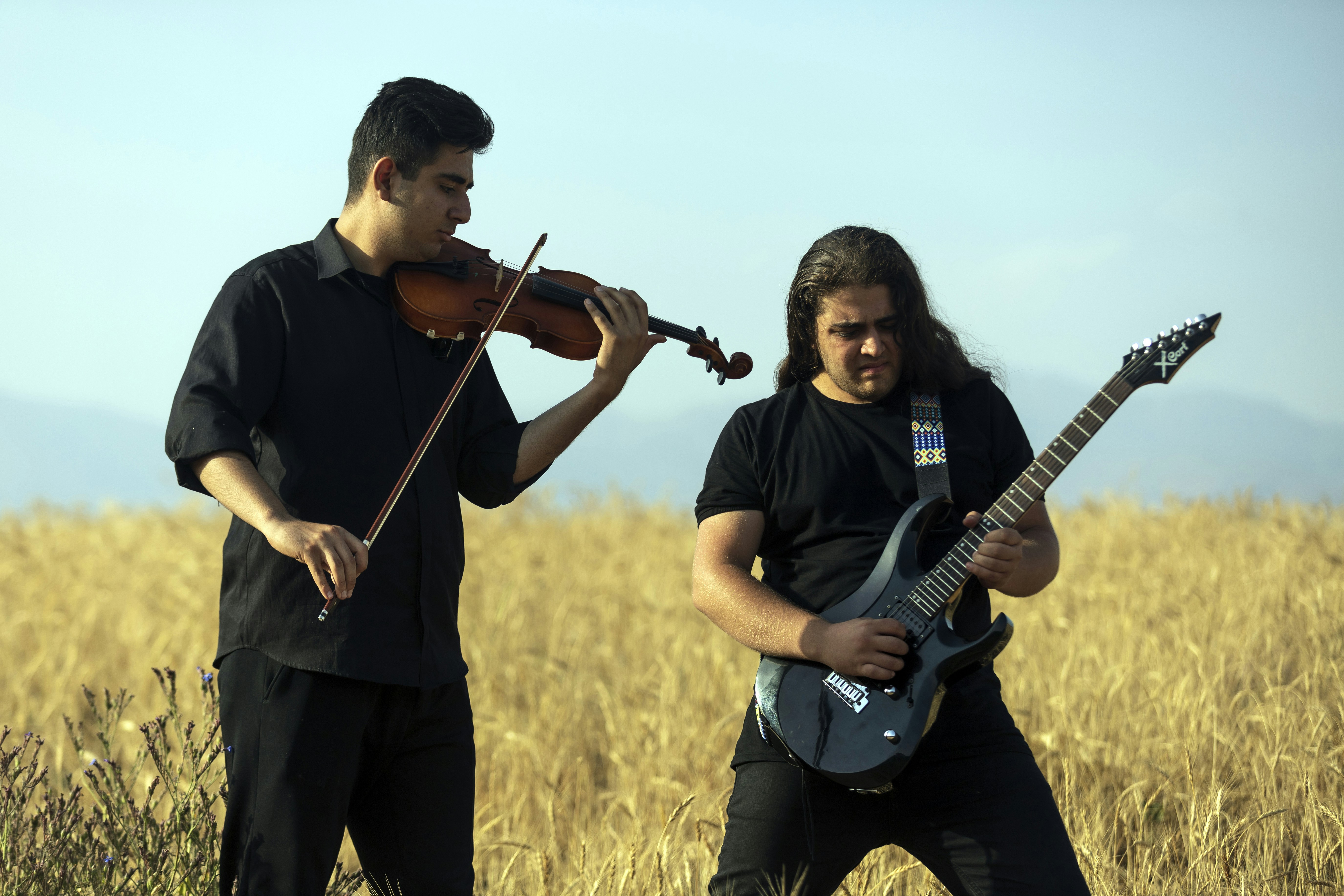 Two musicians playing instruments in a field.