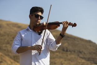 Man playing violin outdoors with sunglasses