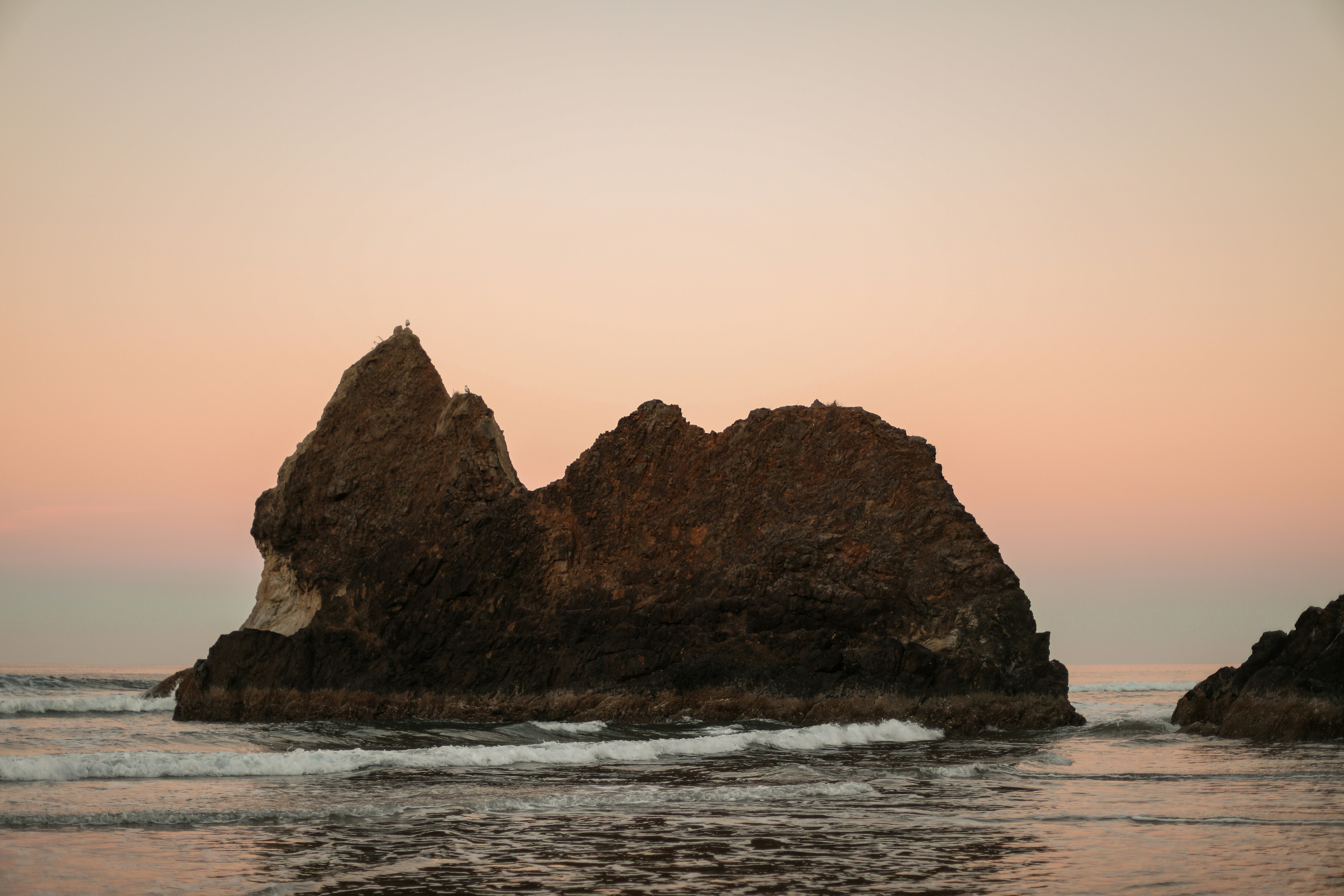 Rock formation in ocean at sunset