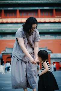 Woman holding child's hand in front of building