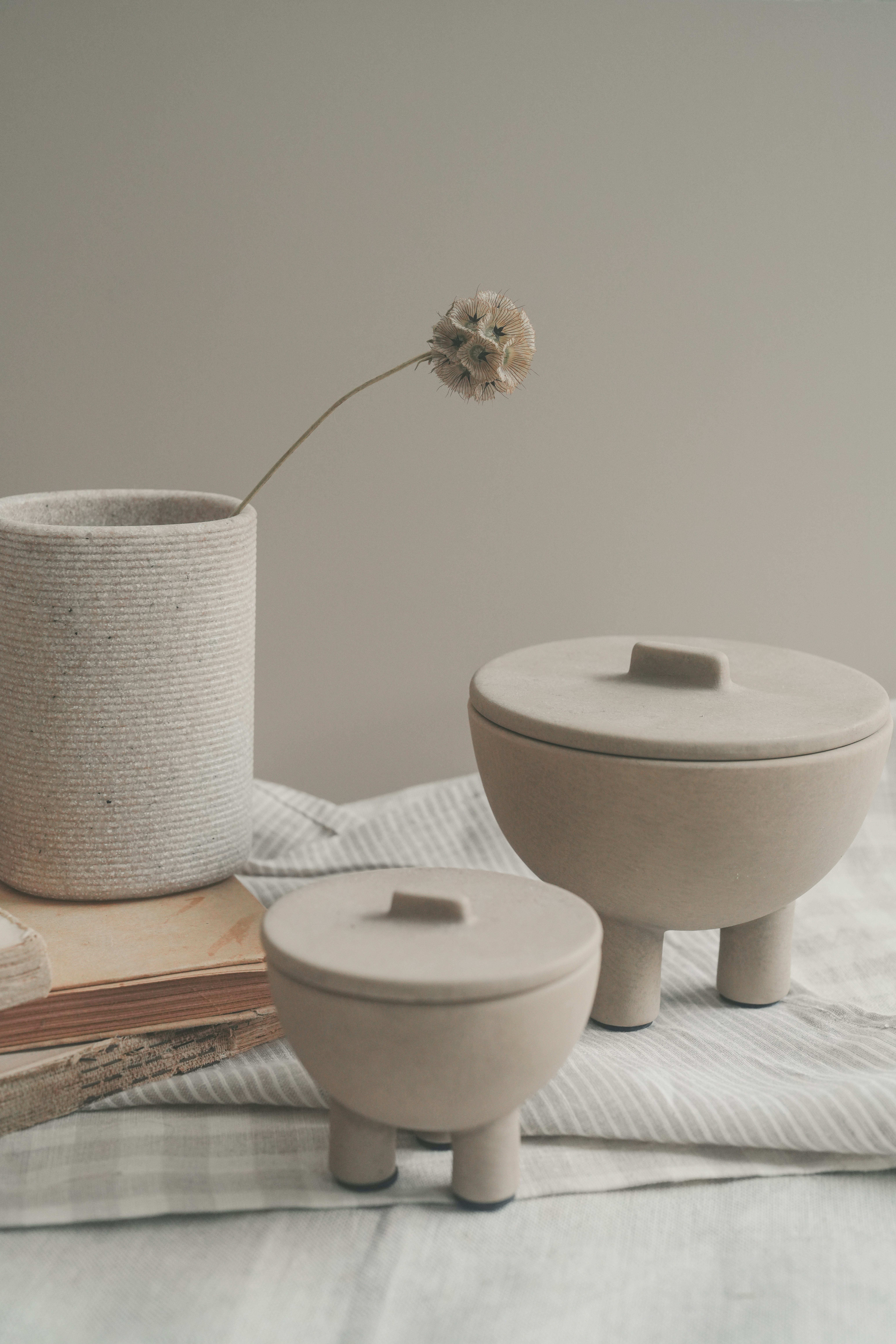 Two lidded ceramic jars with three legs each.
