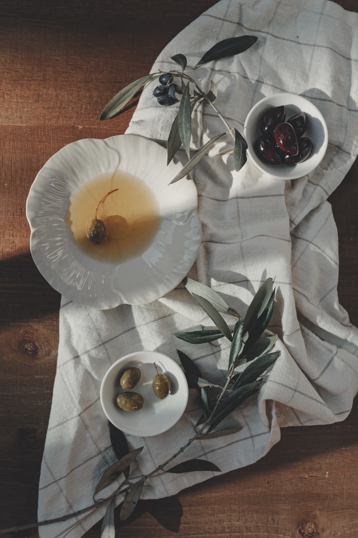 Castelvetrano olives and olive oil arranged on a rustic wooden table.