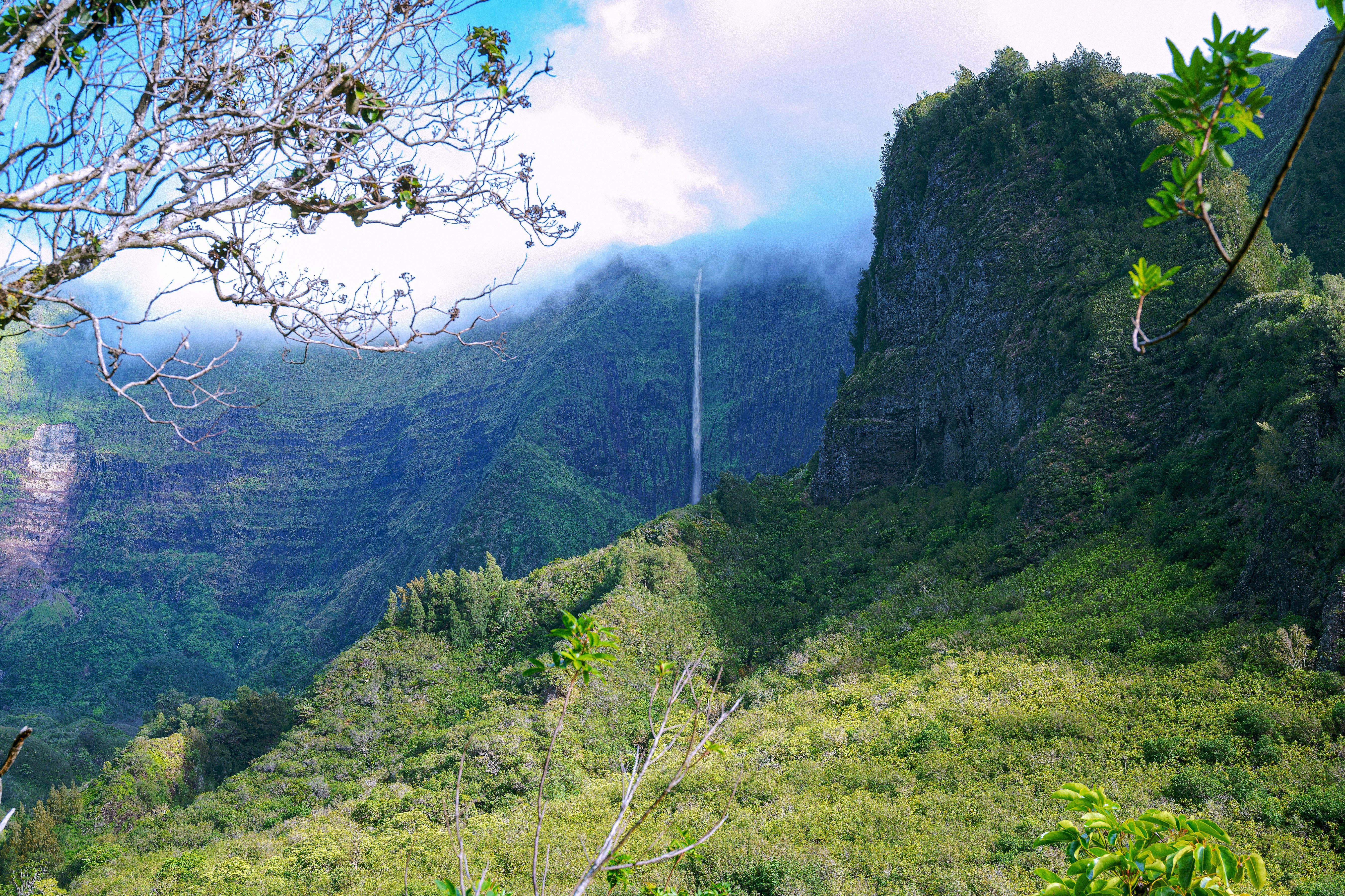 Lush green valley with a tall waterfall cascading down cliffs