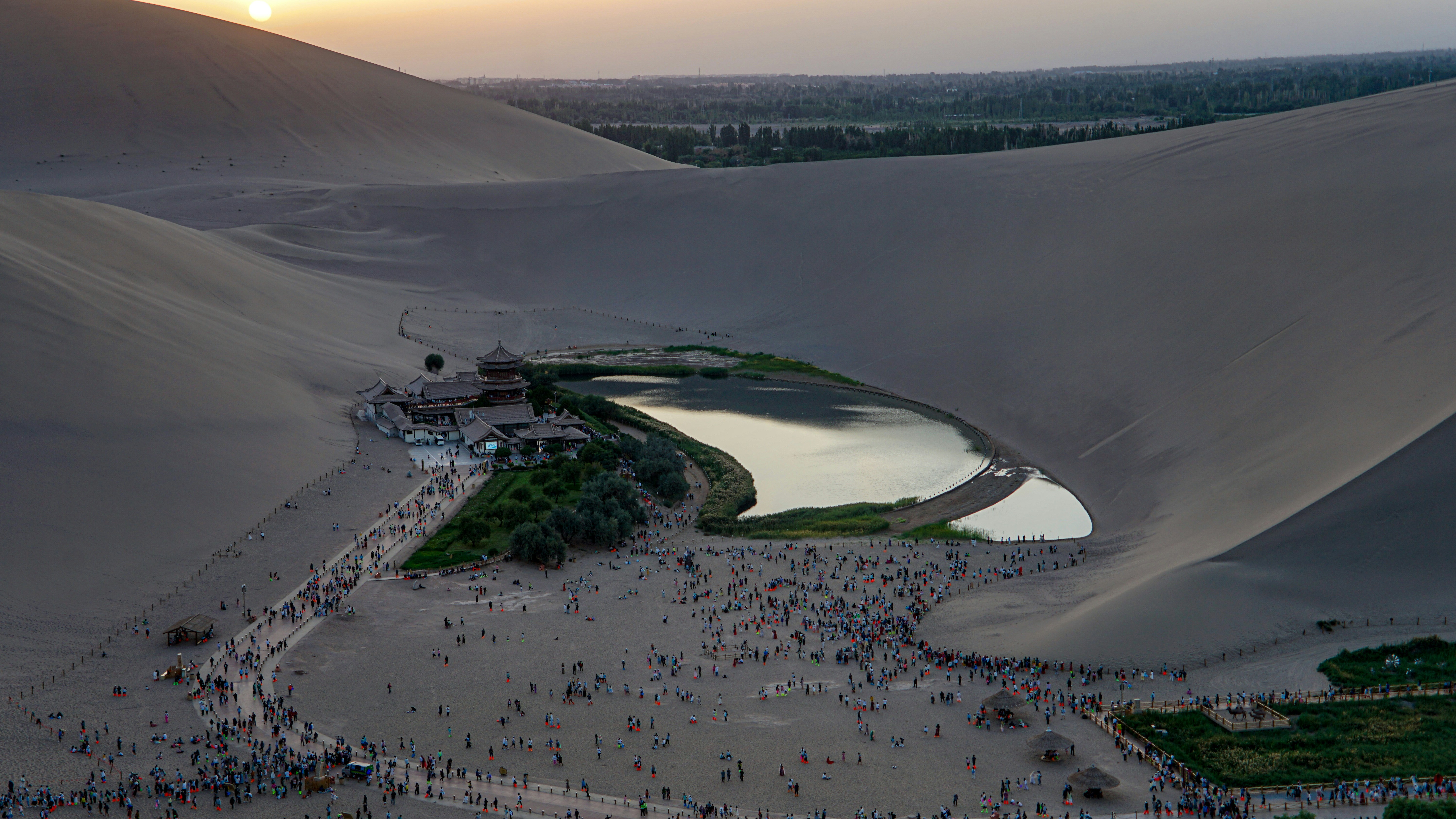 Desert oasis with crescent-shaped lake and sand dunes