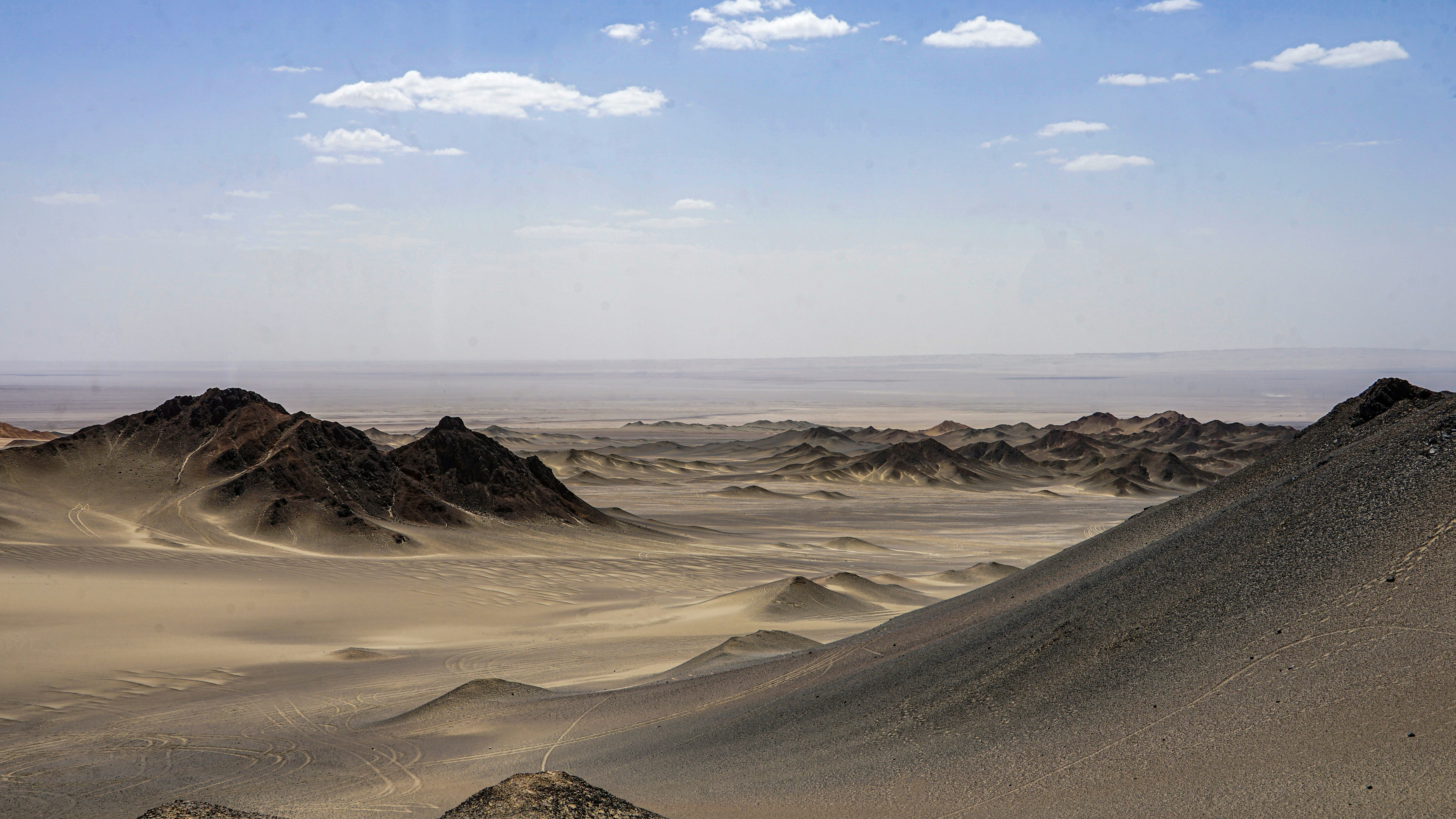 Arid desert landscape with rolling sand dunes and mountains.