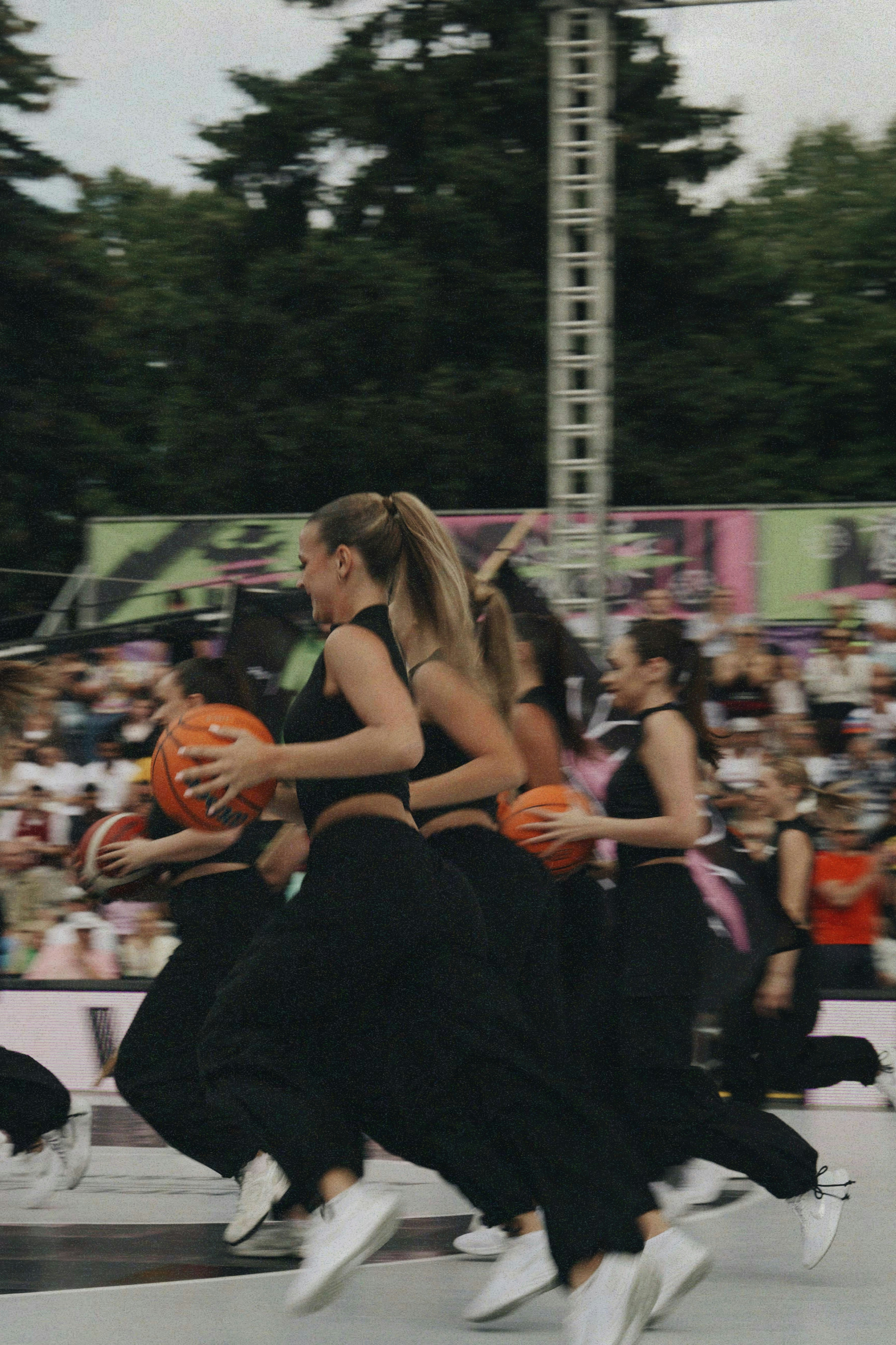 Women in black outfits playing basketball outdoors