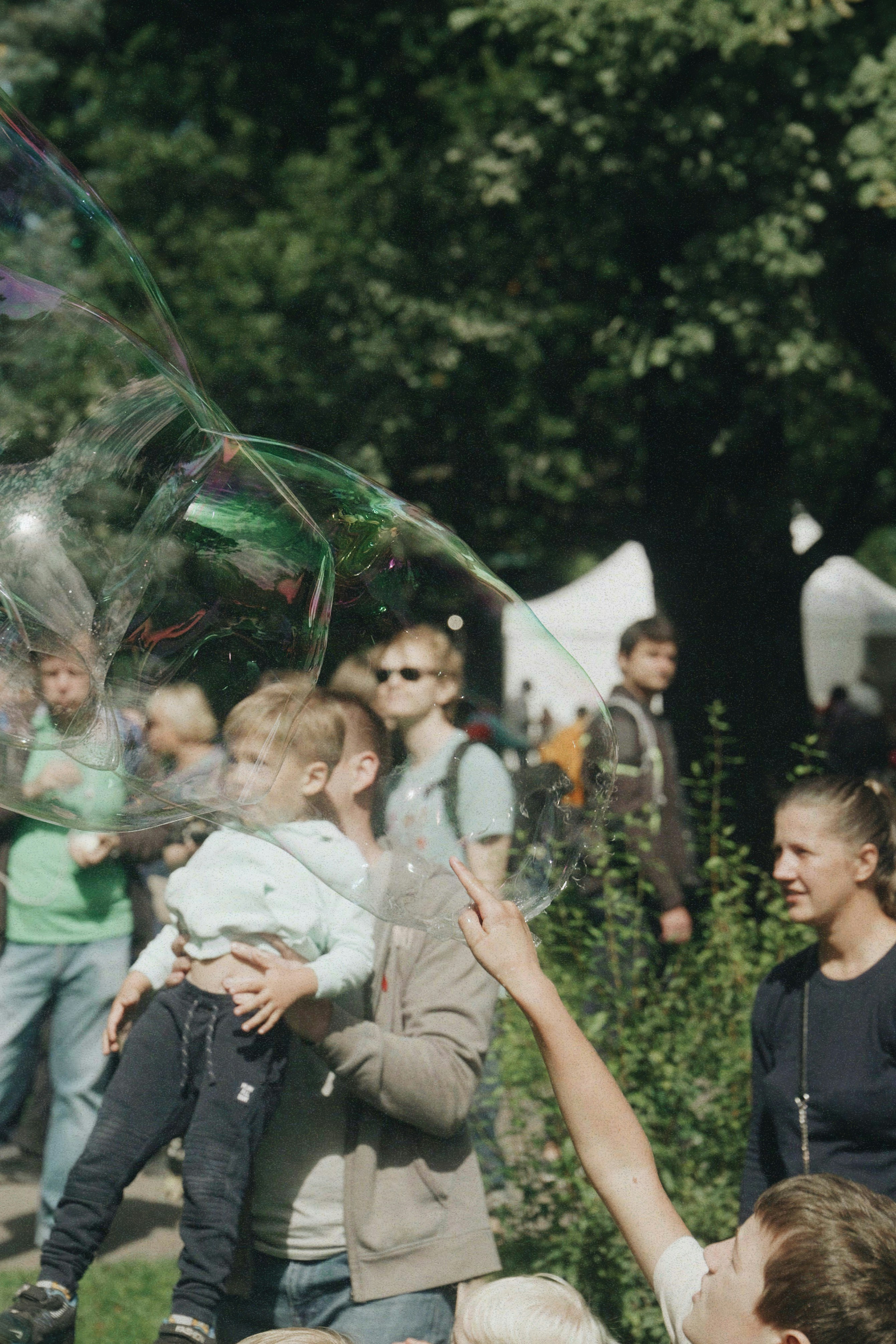 Children and adults watching large bubbles float
