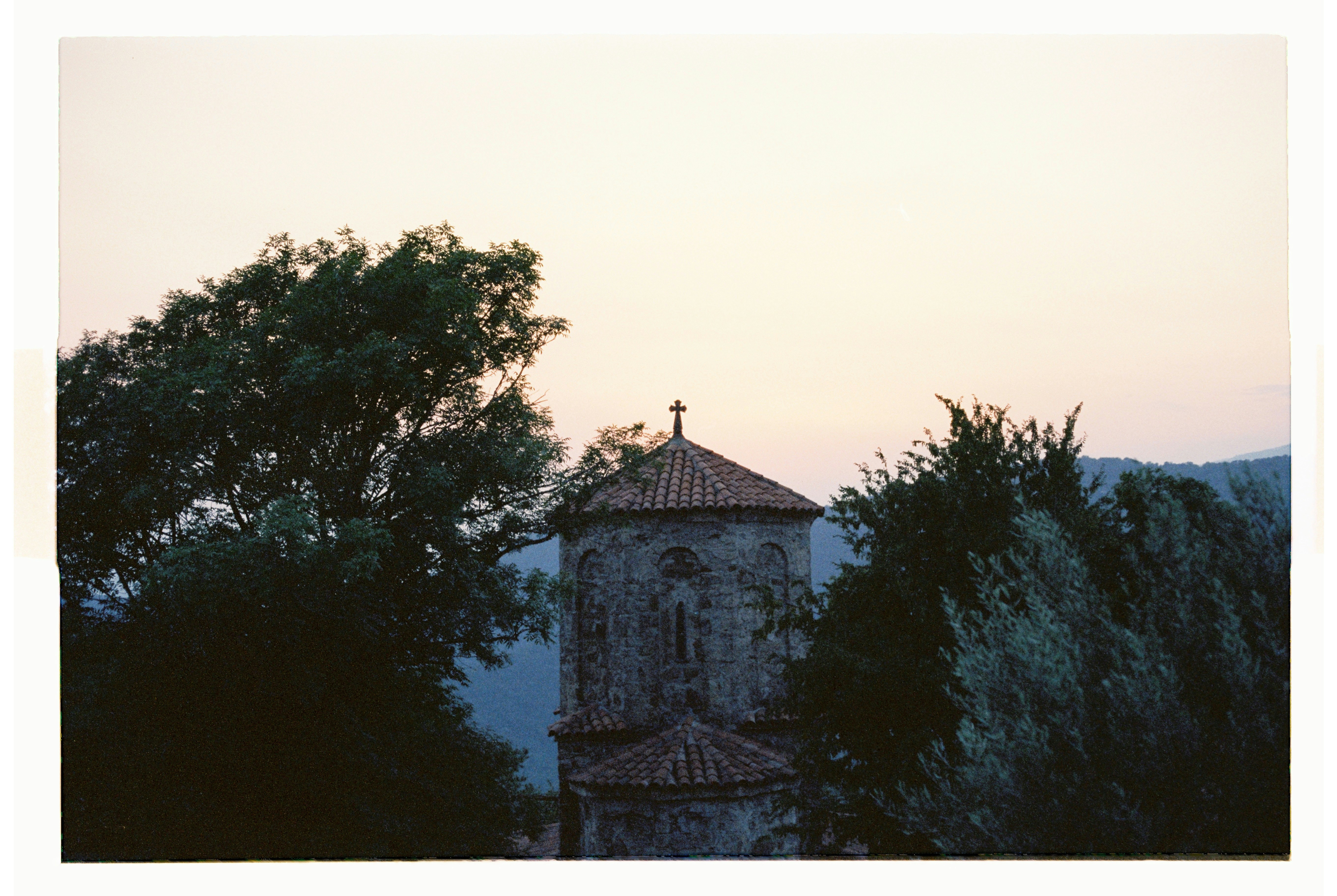 Ancient stone tower with cross against pale sky