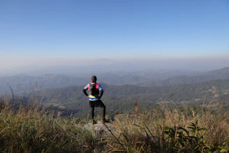 Hiker stands on a mountain overlooking a hazy landscape.