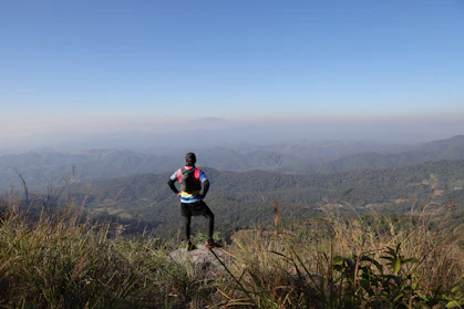 Hiker stands on a mountain overlooking a hazy landscape.