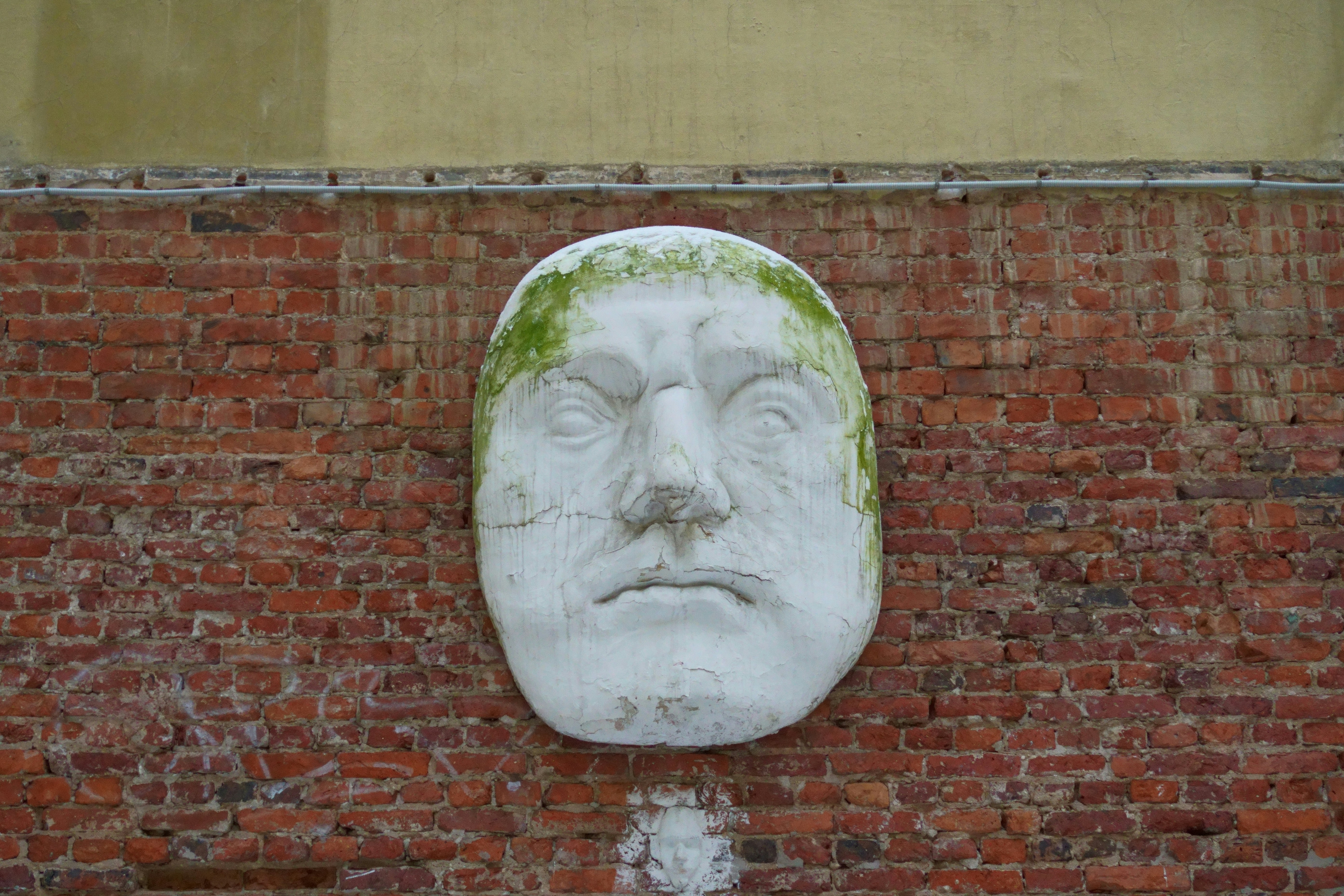 White plaster face mask on brick wall