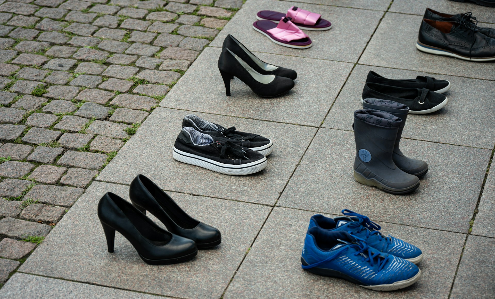 Assortment of shoes arranged on pavement