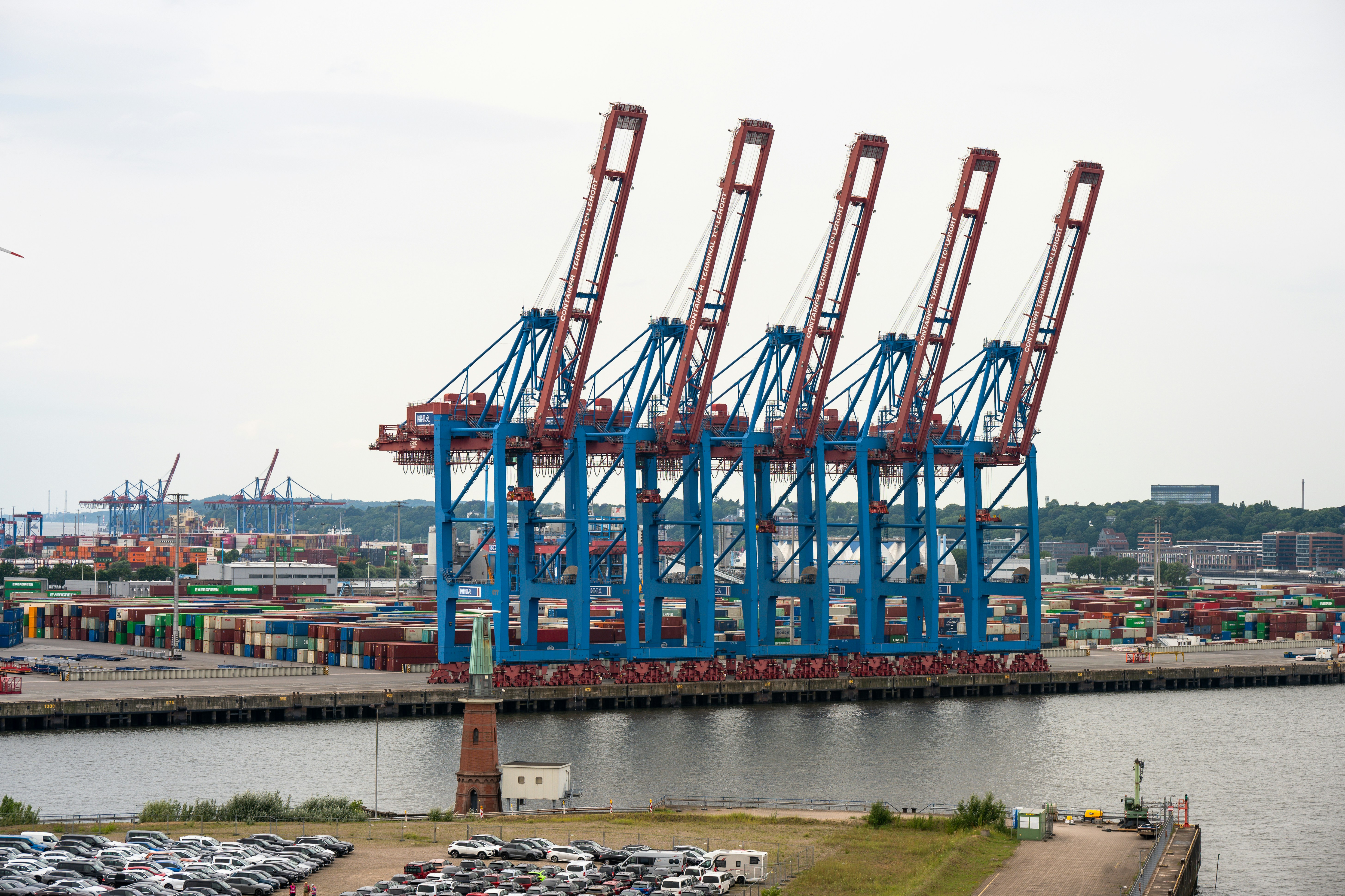 Beberapa derek pelabuhan biru besar berdiri di tepi air.