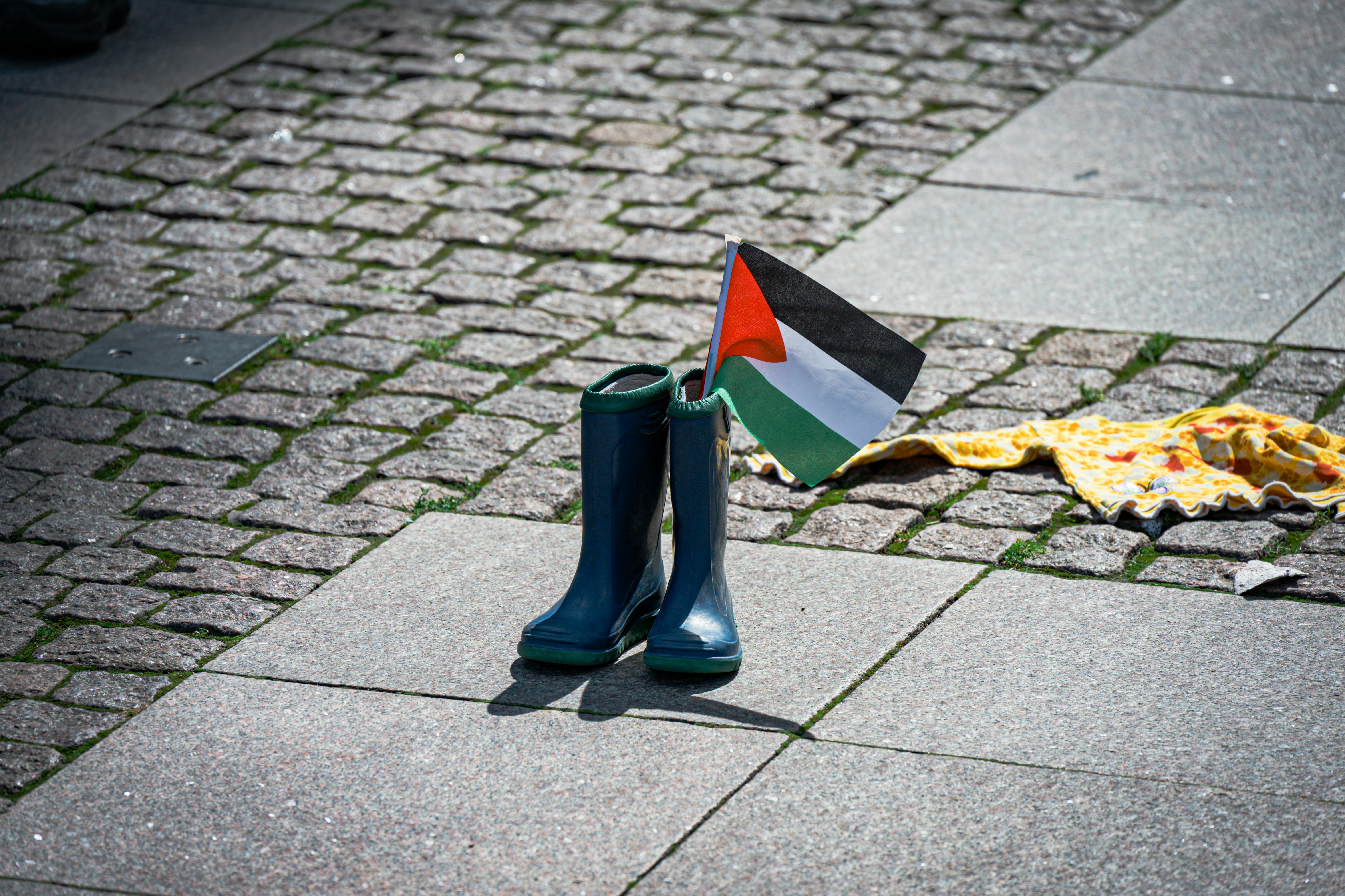 Blue boots with palestinian flag on pavement