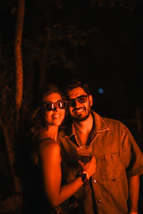 Couple wearing sunglasses at night with drink