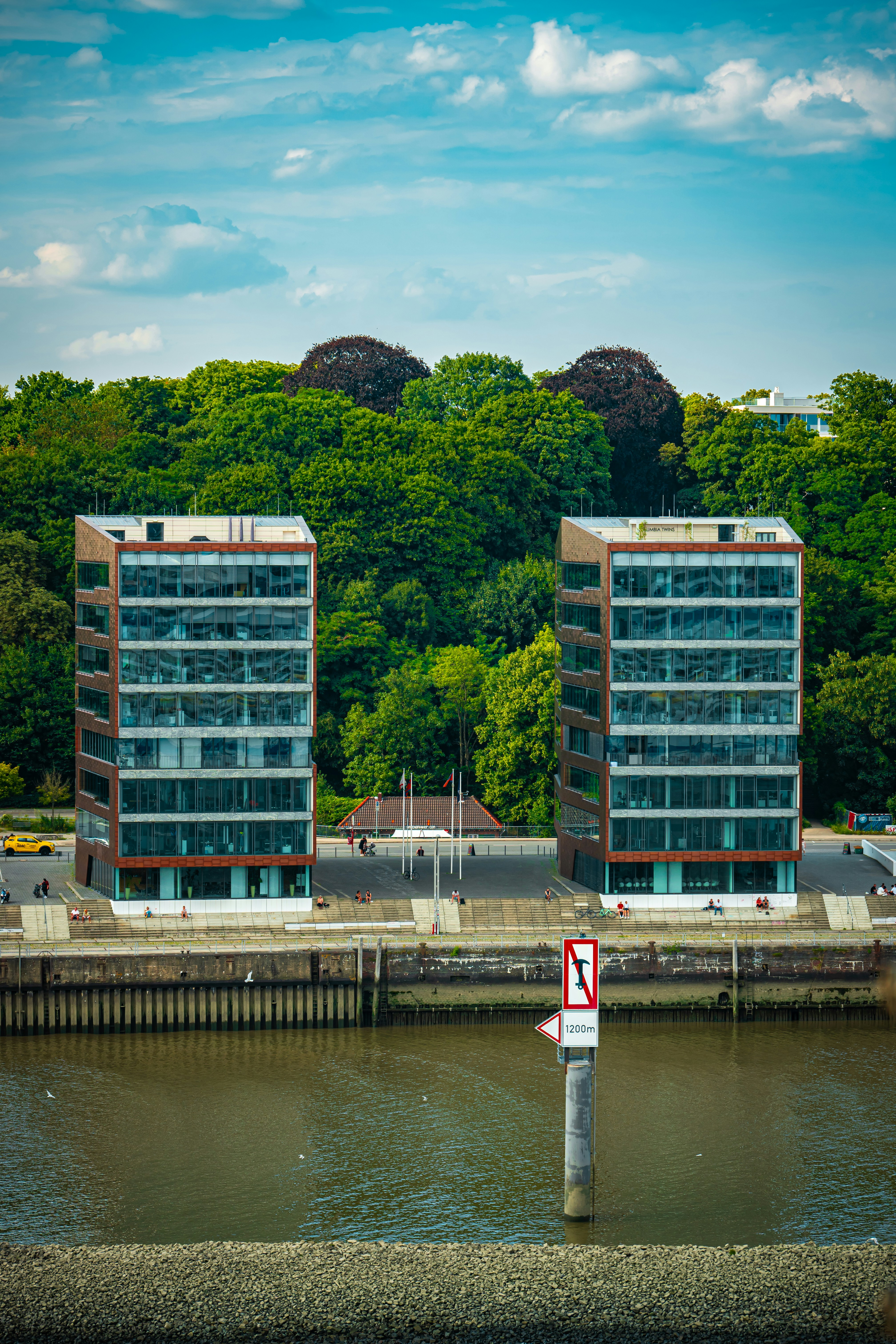 Two modern buildings stand beside a calm river