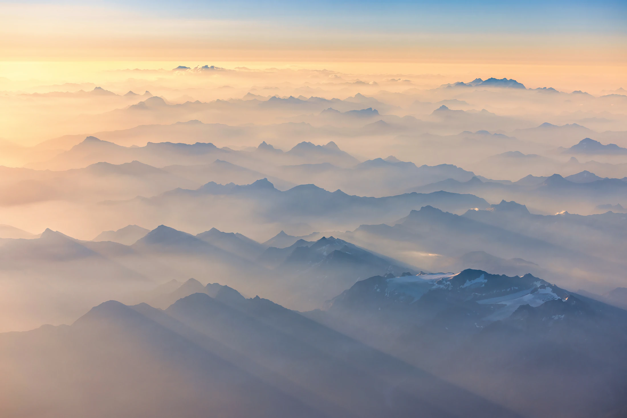 Mountain range peaks emerging from a sea of cloud at sunrise