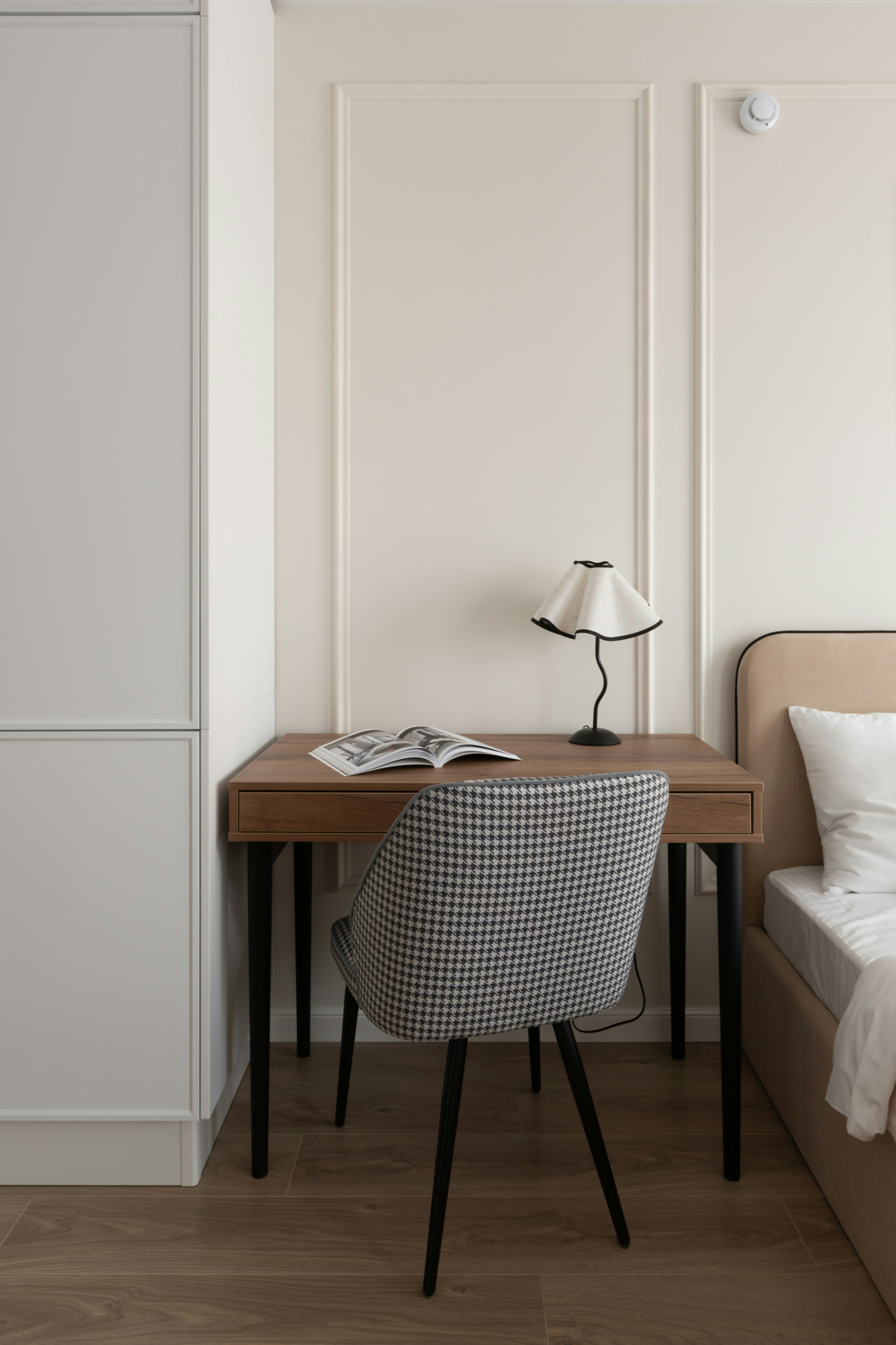 A desk with a chair, lamp, and book.