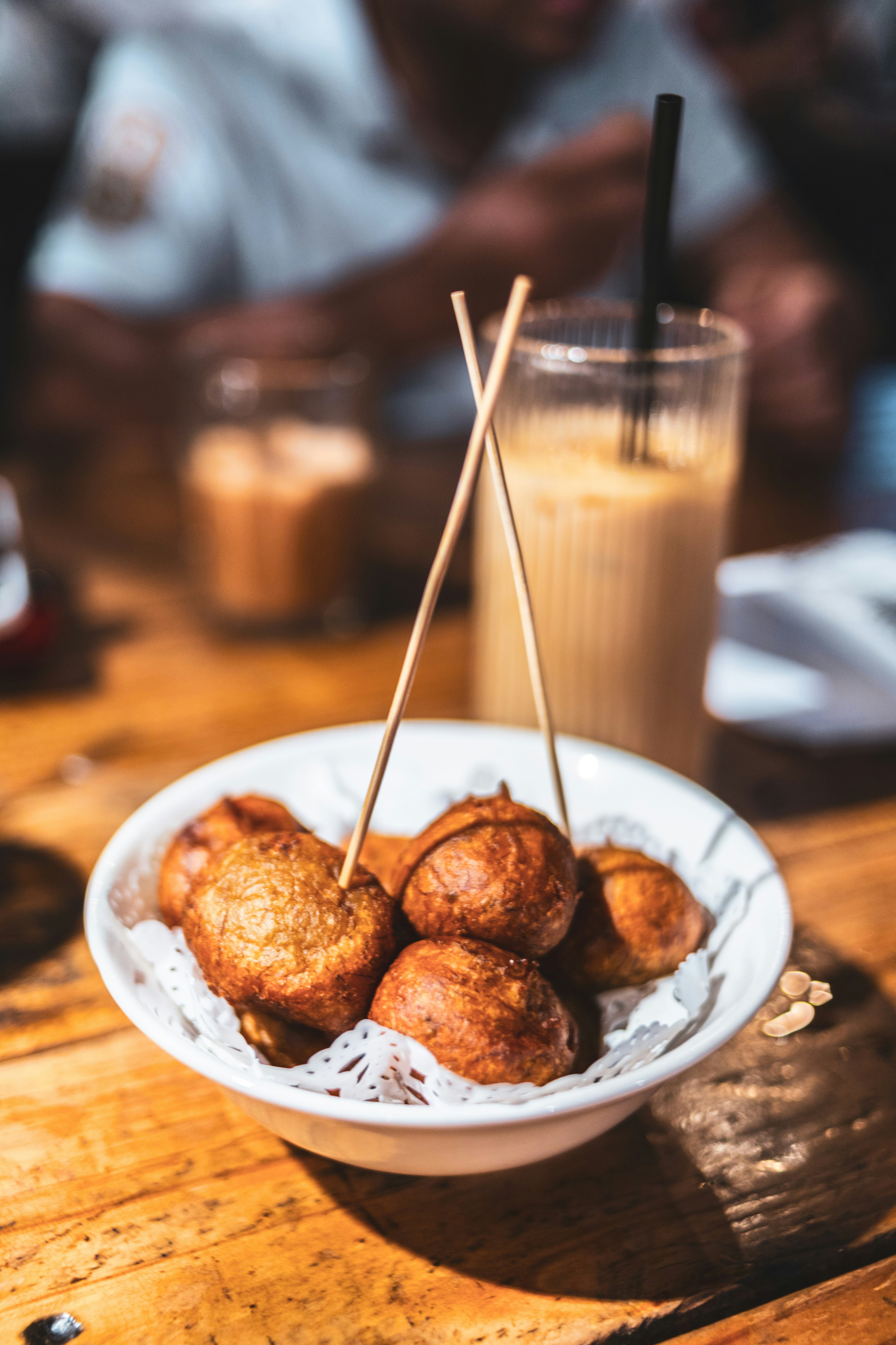 Fried dough balls served in a bowl with skewers.
