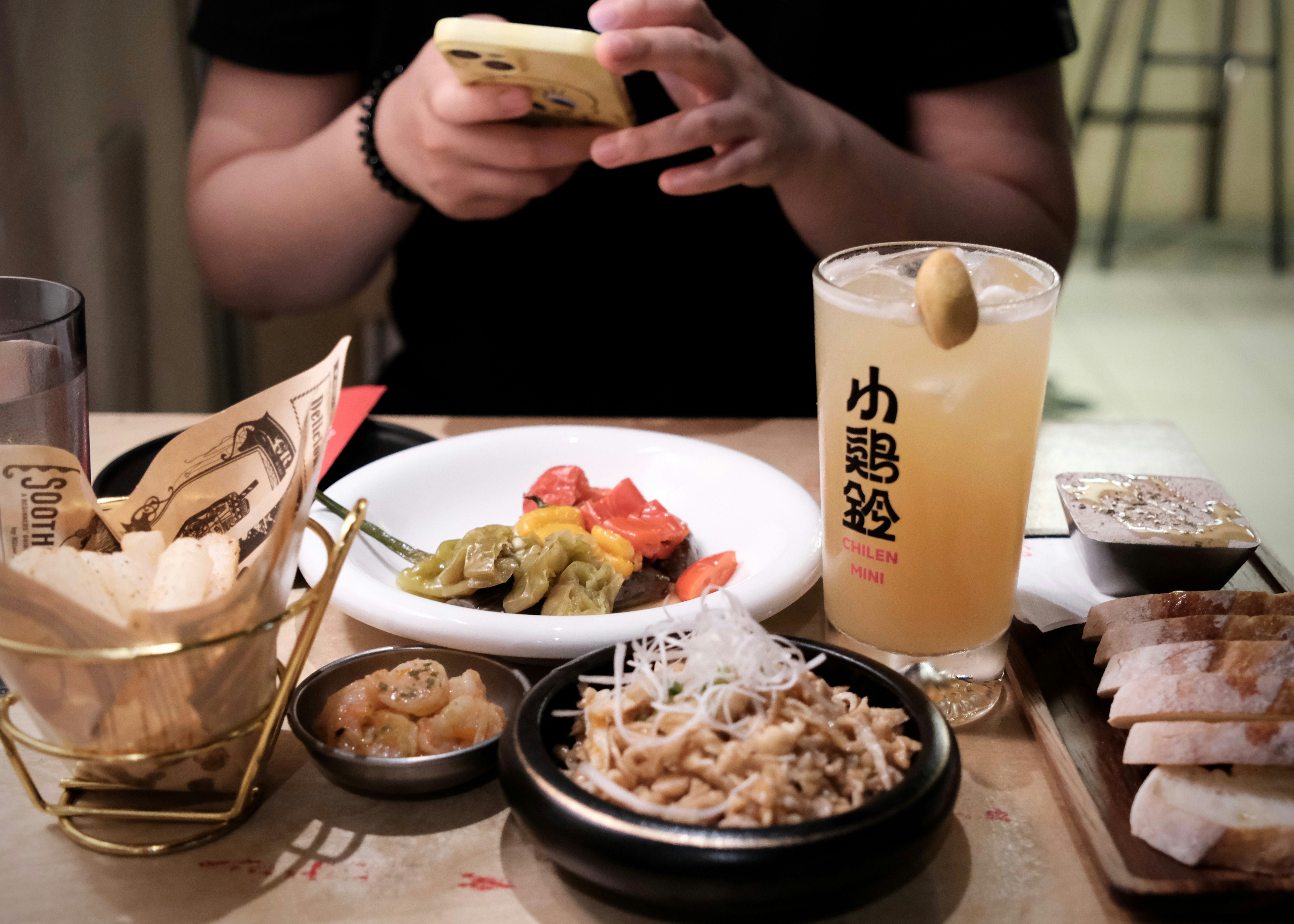 Table with food and drink, person using phone