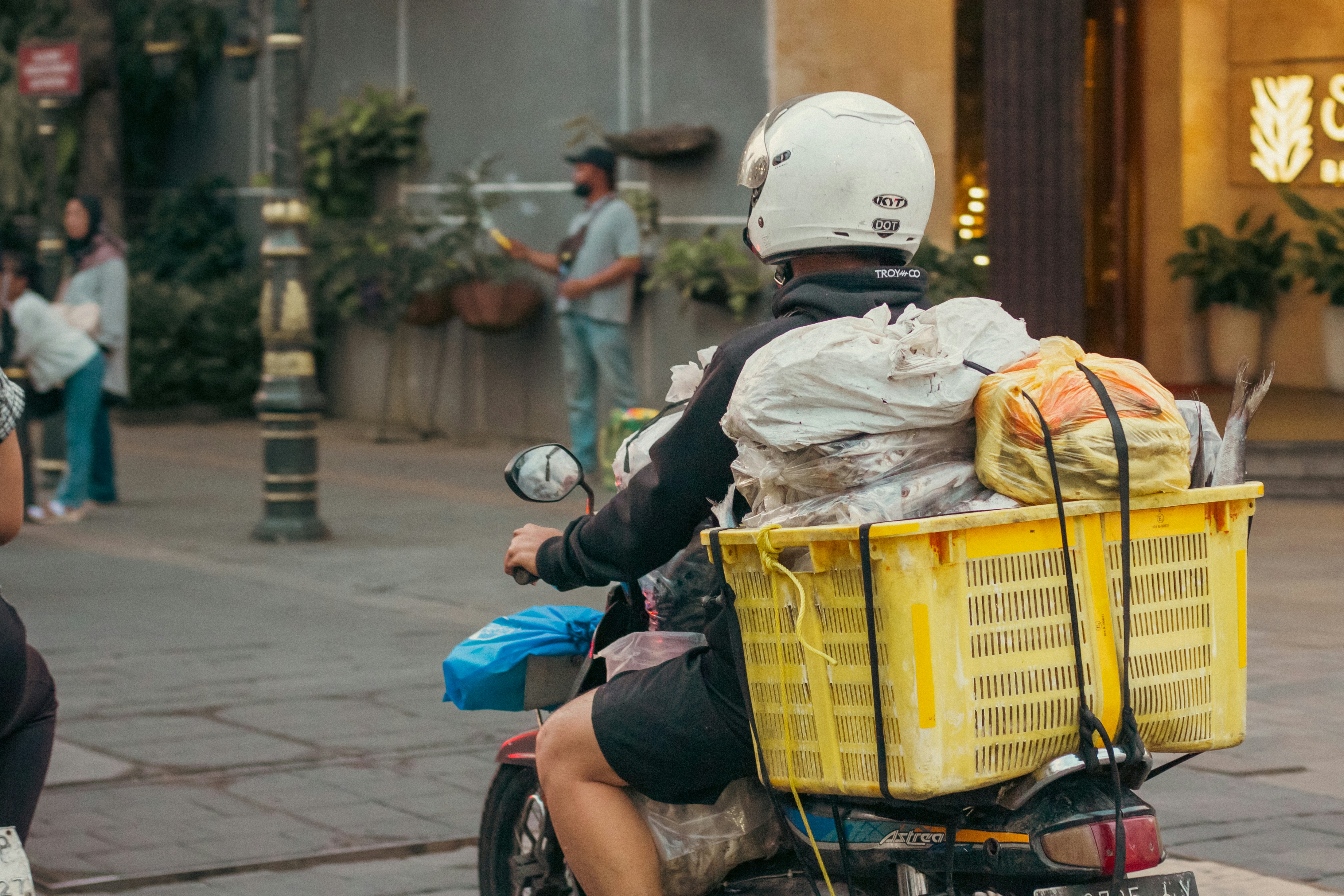 Motorcyclist with a large yellow basket of goods.