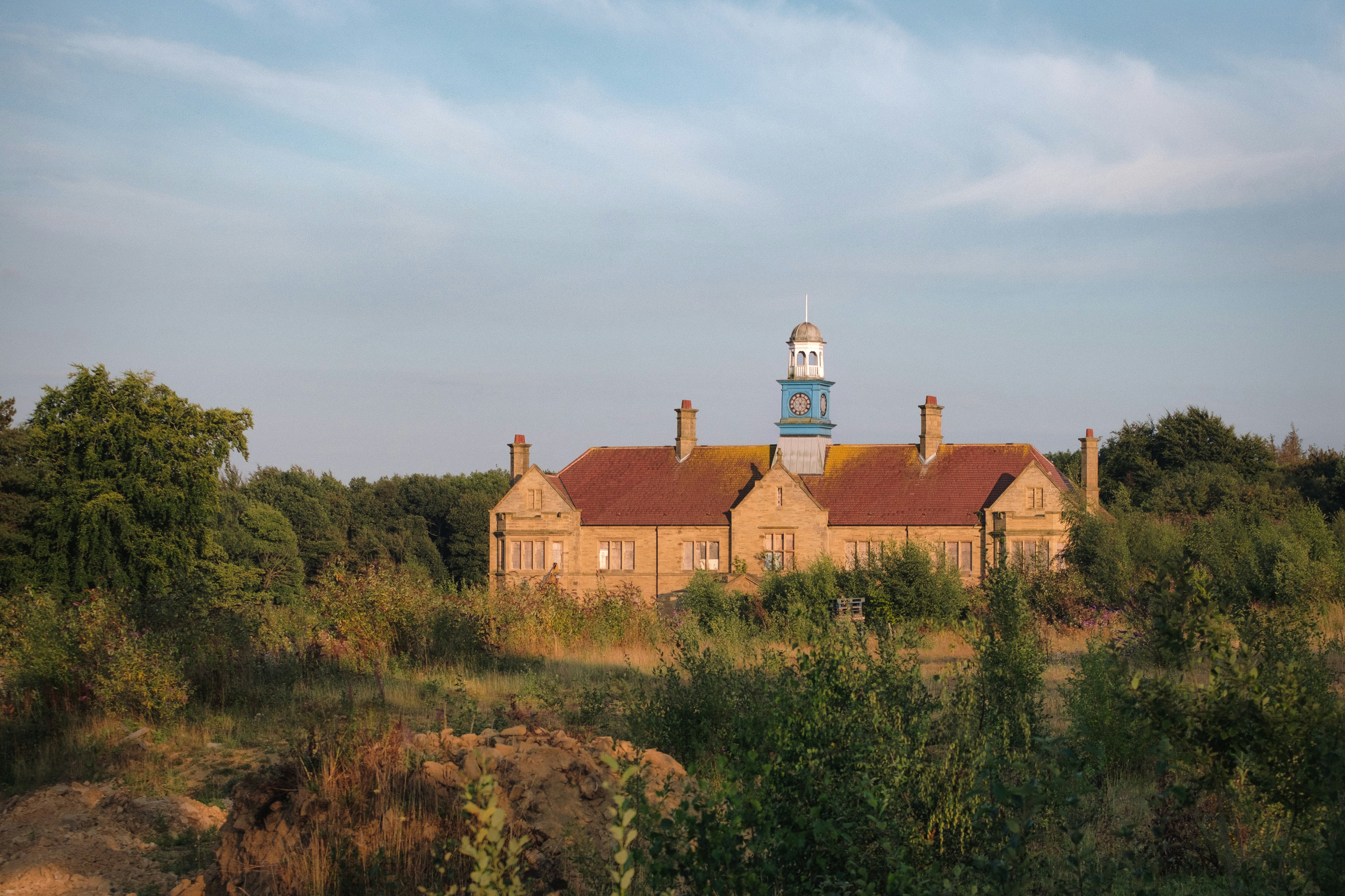 Altes Gebäude mit blauem Turm, umgeben von Bäumen
