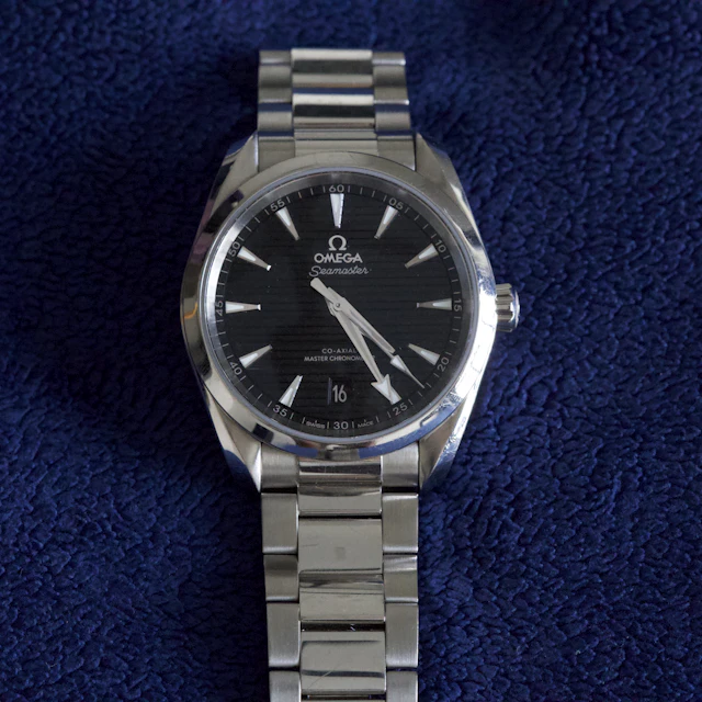 A silver Omega wristwatch with a black face photographed close up