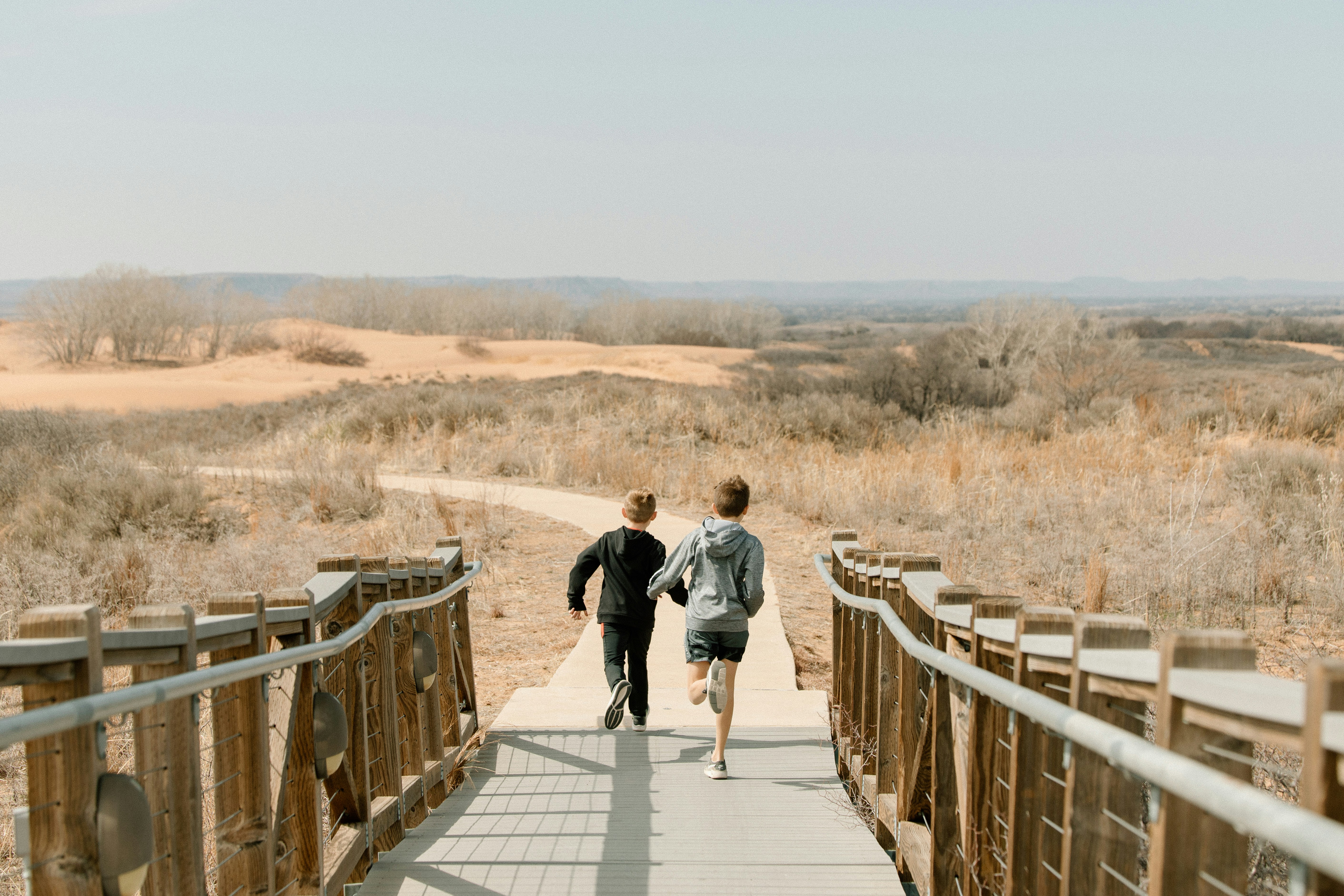 屋外の木橋の上を走る2人の少年