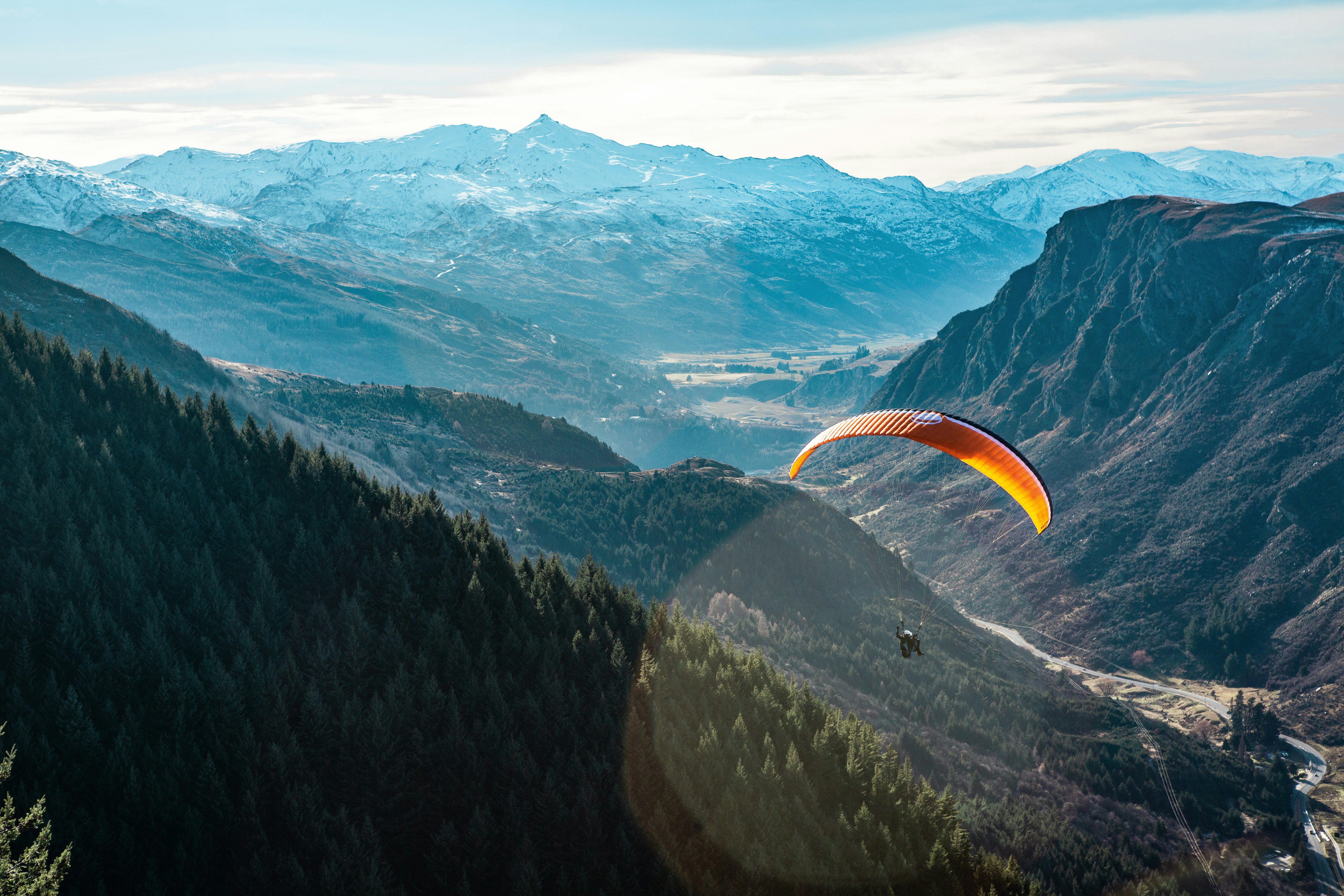 Paraglider soaring over a vast mountain valley