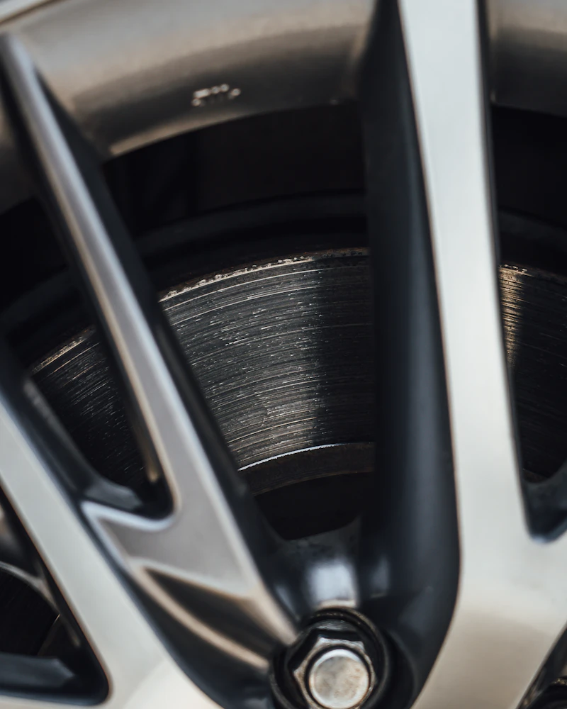 Close-up of a silver alloy wheel spoke and lug nut, with the brake rotor behind it.