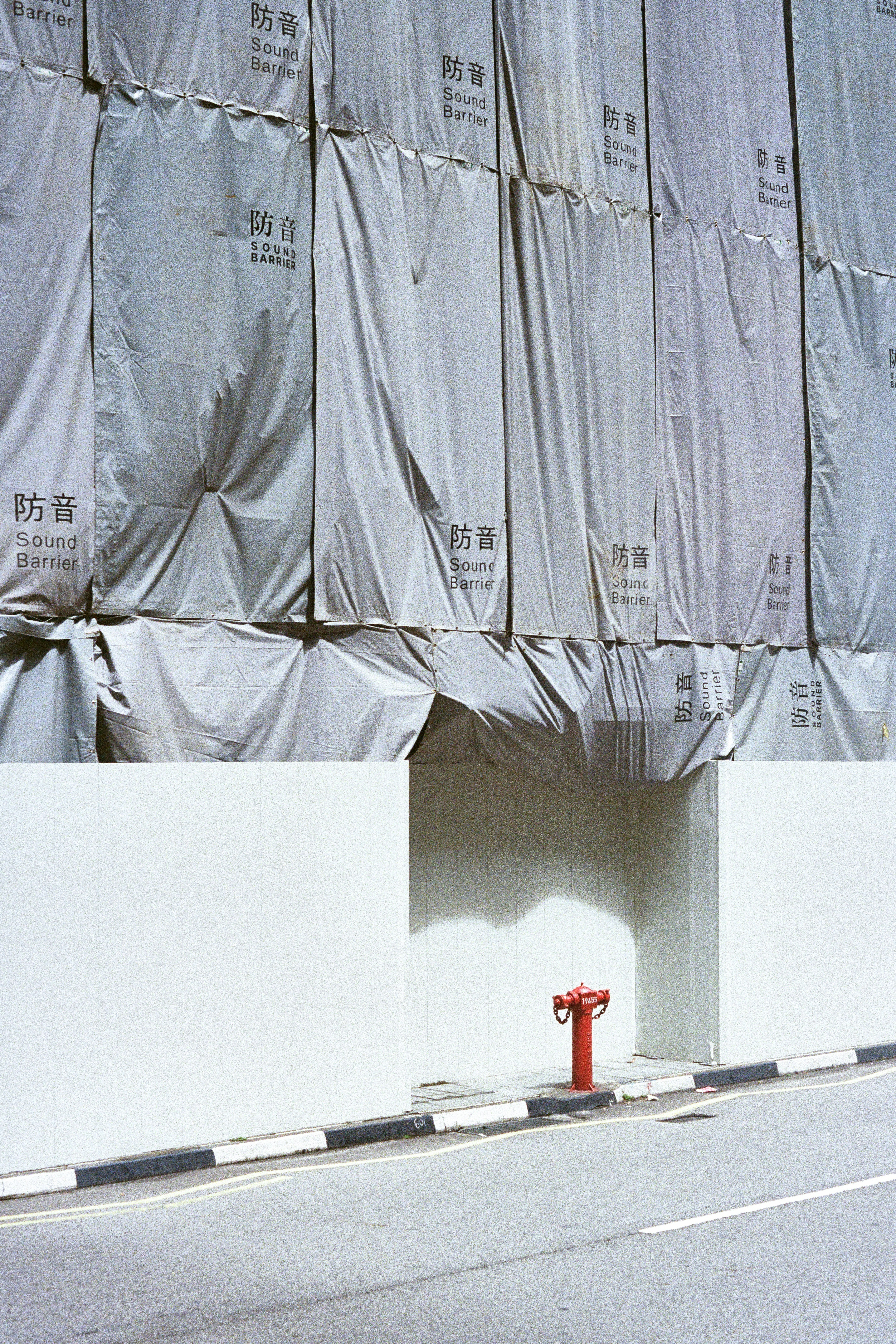 Red fire hydrant against white wall and draped building