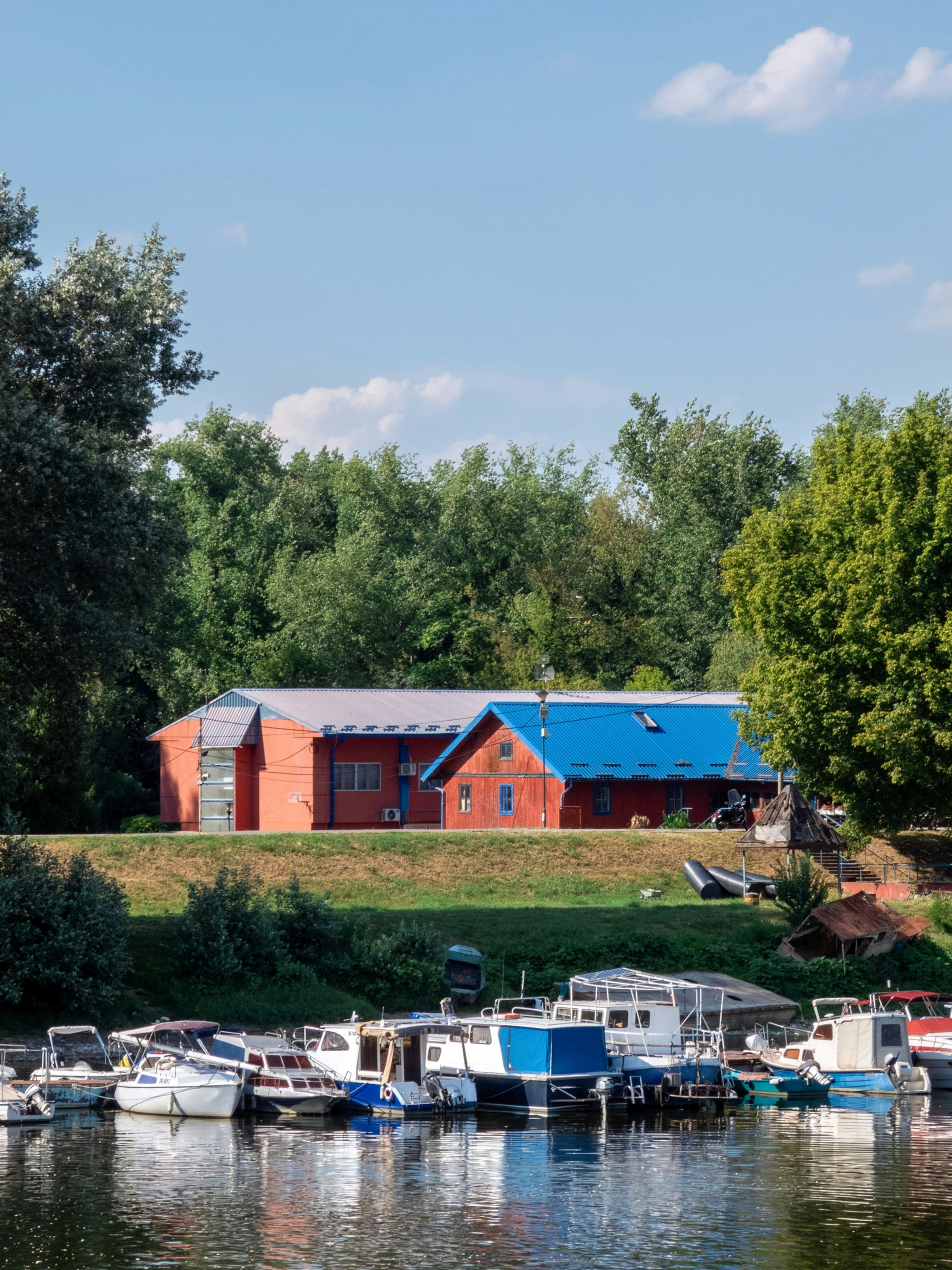 Boats docked at a river with buildings and trees