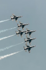 Six fighter jets flying in formation with smoke trails