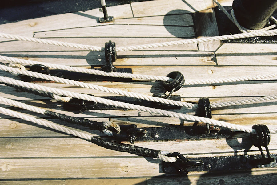 Thick weathered ropes running through wooden blocks and pulleys on a sailing boat's deck.