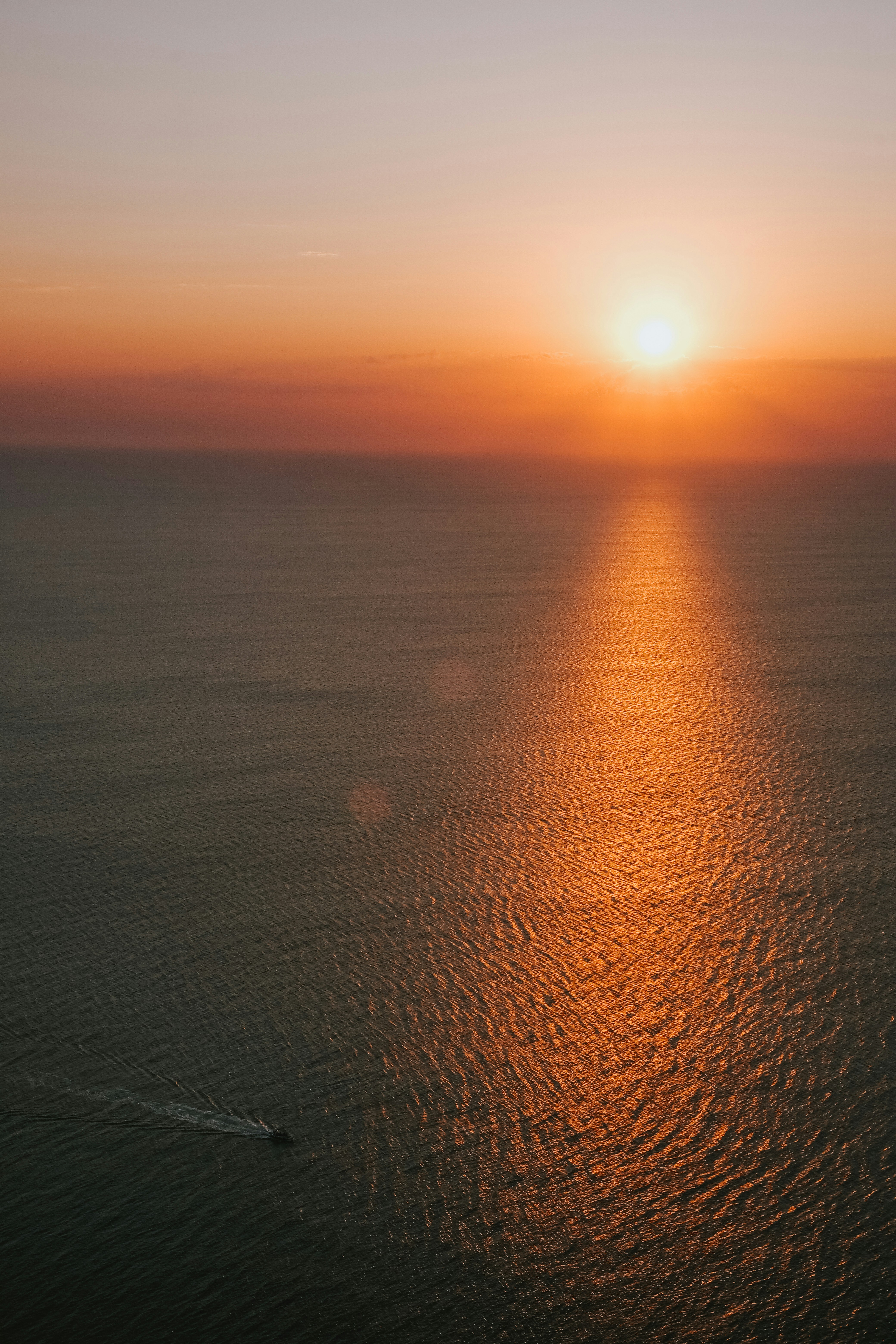 Sunset over a calm ocean with a distant boat