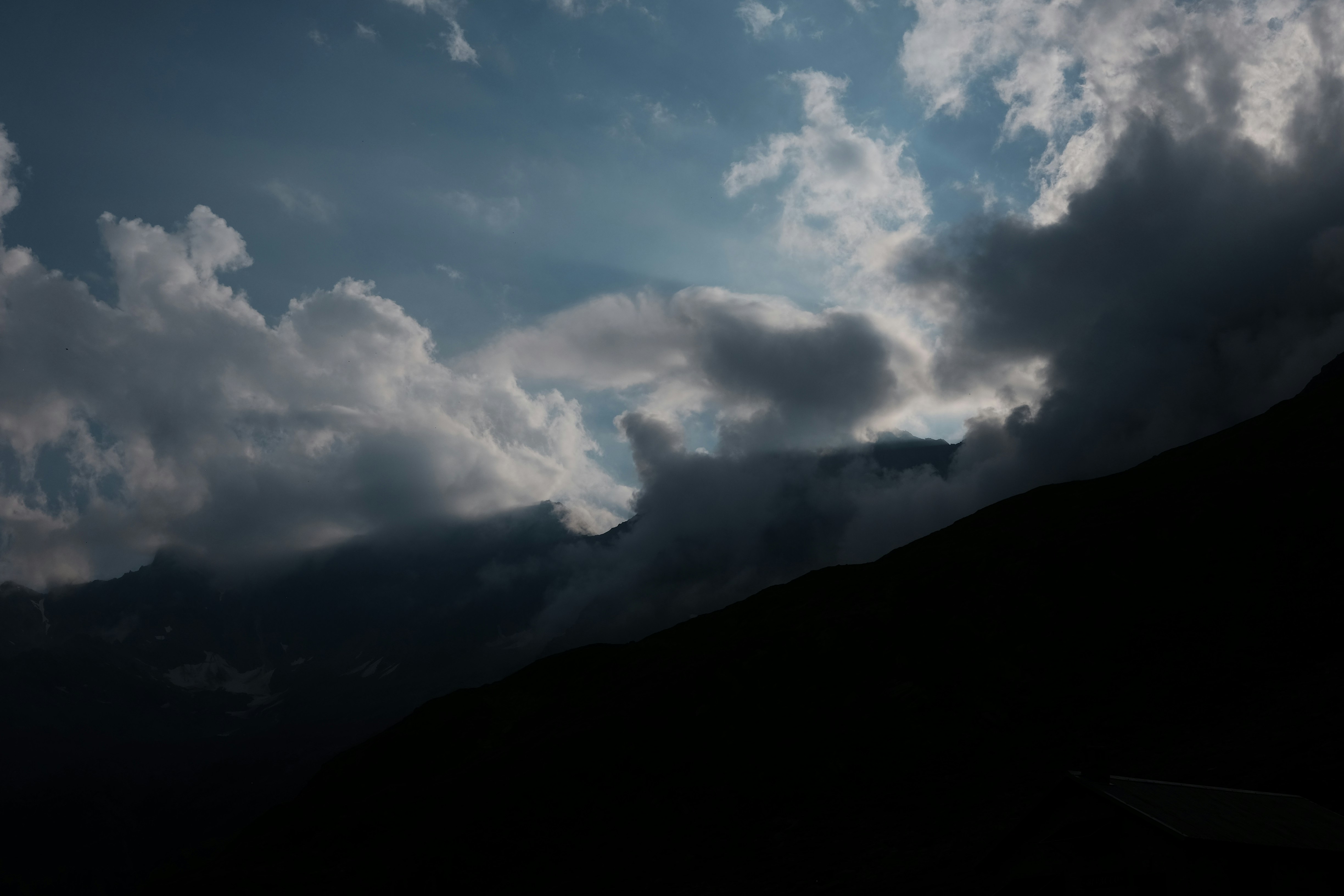 Dark clouds obscure a mountain landscape at dusk.