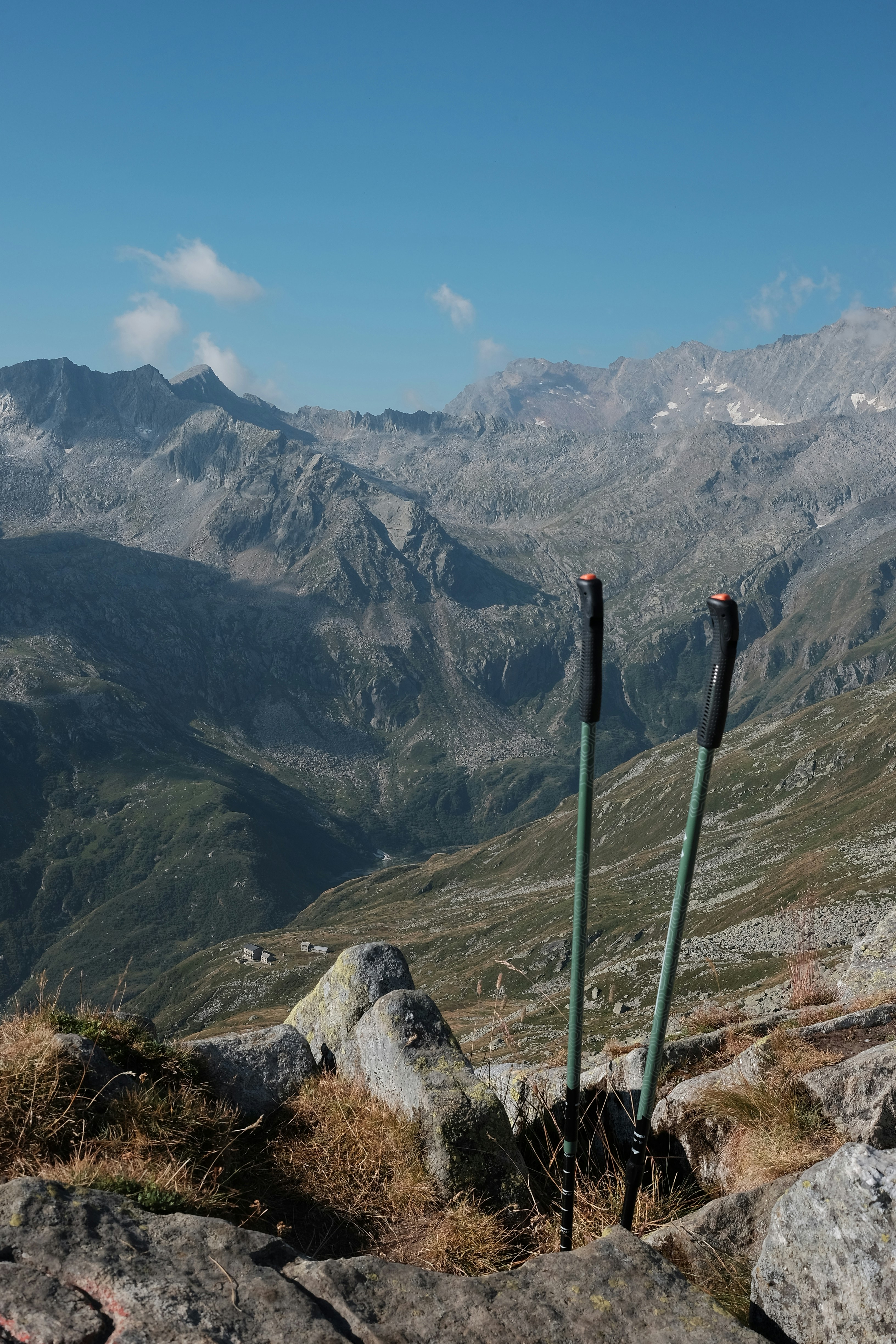 Trekking poles stand on rocky mountain ridge overlooking valley view