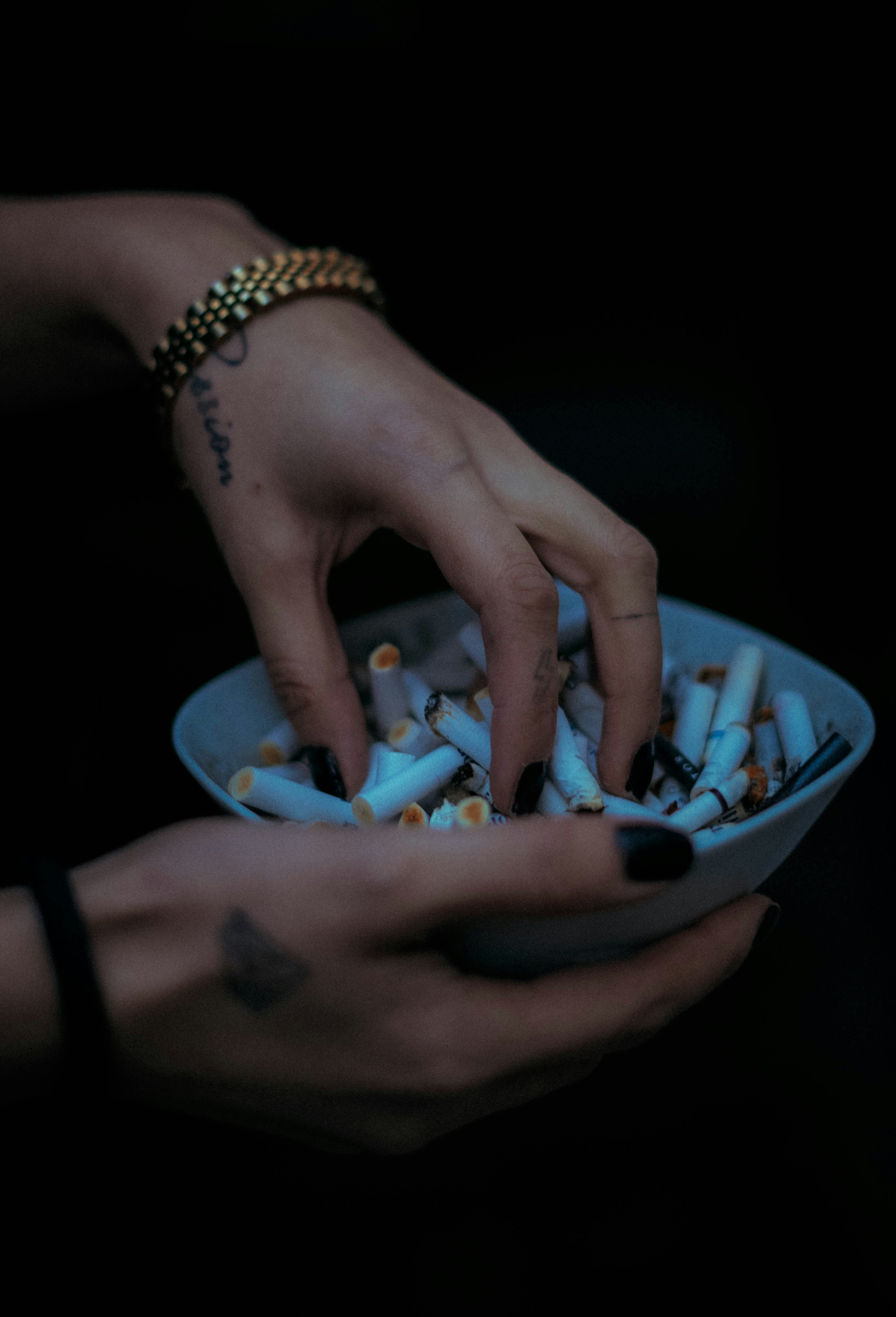 Smokers hands and cigarettes, ilustrasi artikel Unmasking the Link: How Smoking and Alcohol Fuel Your Acne 5