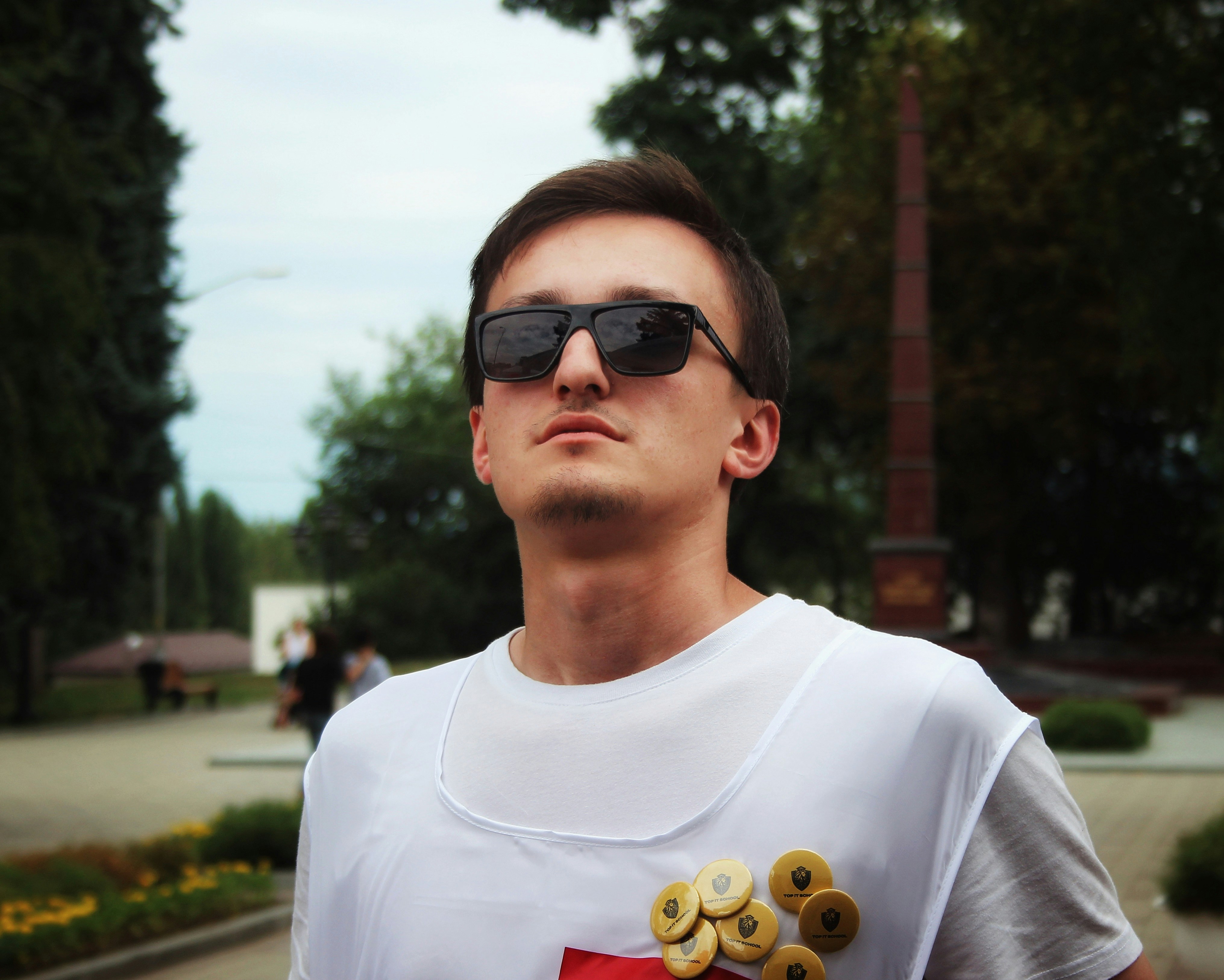 Young man wearing sunglasses and a white vest.