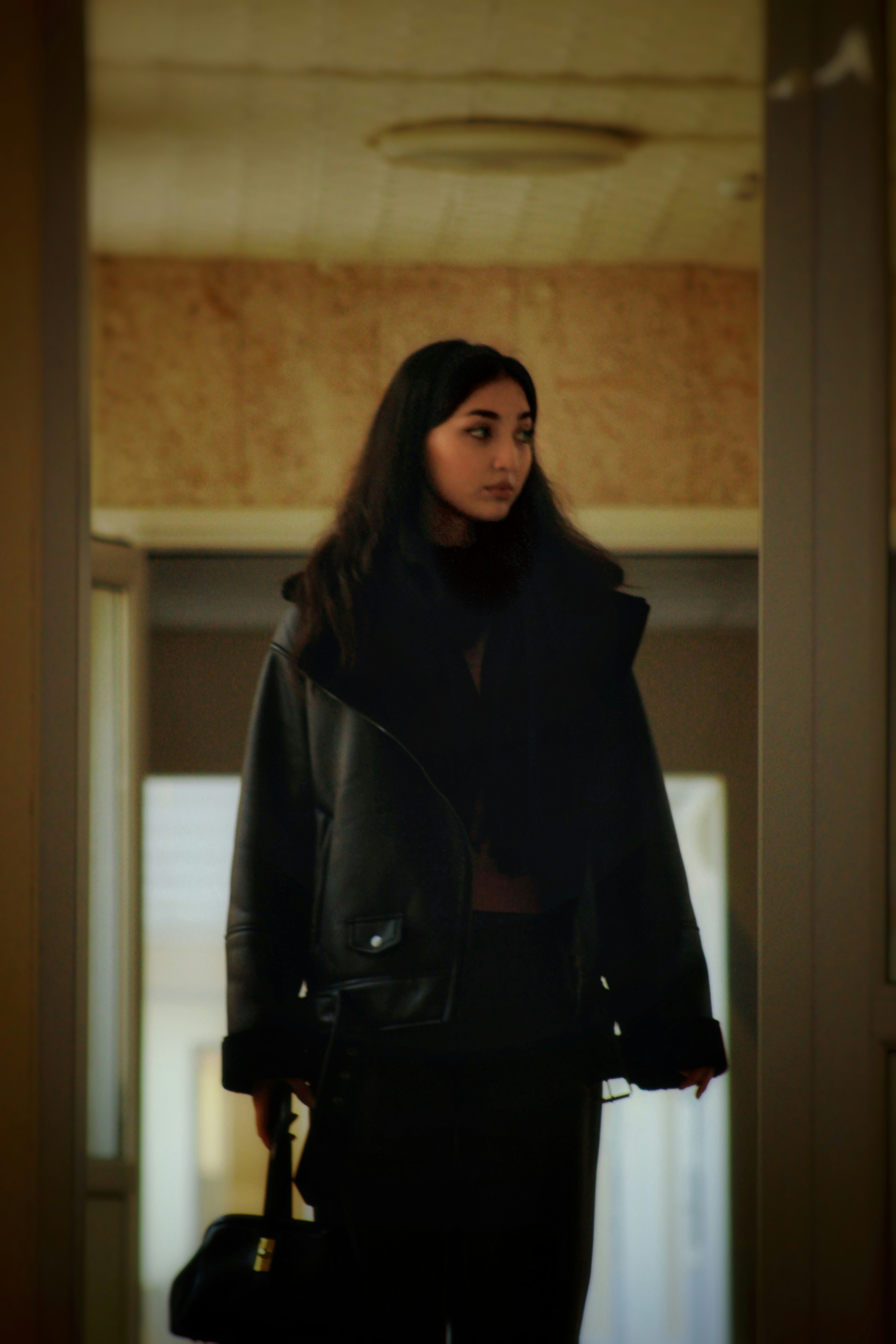 Young woman in a black jacket holding a bag
